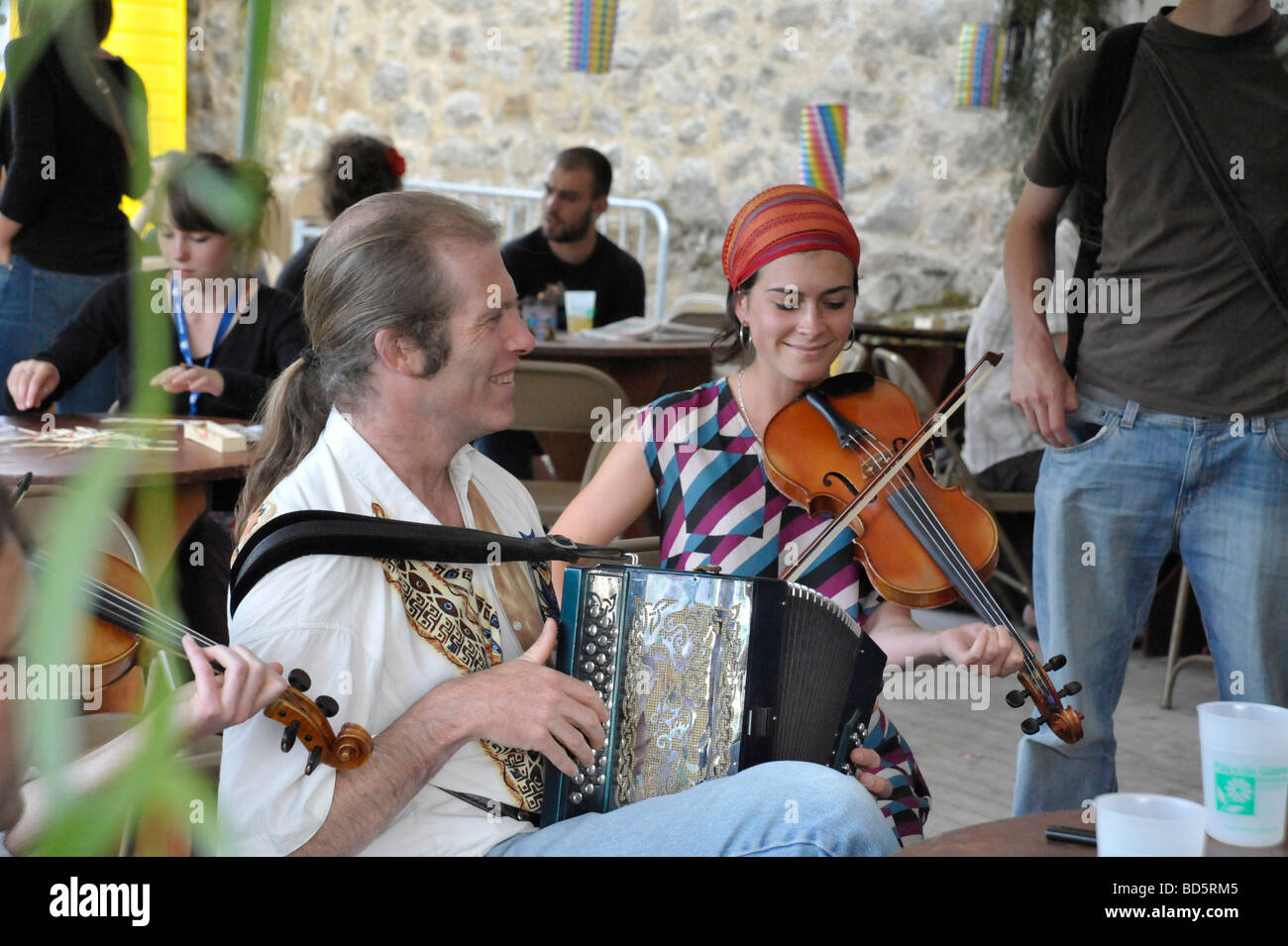 Folk diatonic accordionist and fiddle musicians enjoying a musical jamming session in French bar Stock Photo