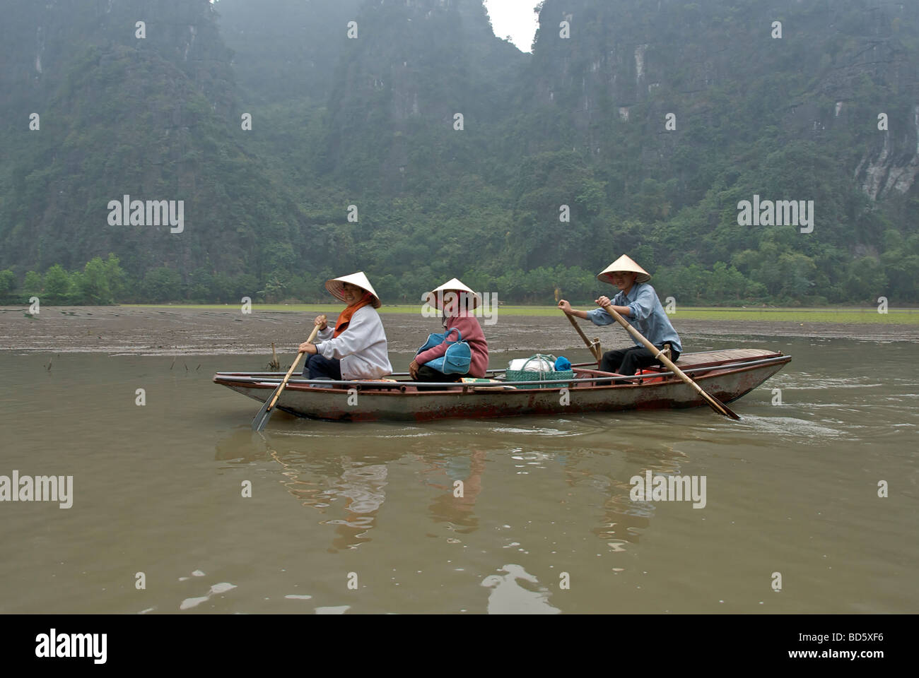 Three Vietnamese in rowing boat Ngo Dong River Tam Coc Ninh Binh Province Northern Vietnam Stock Photo