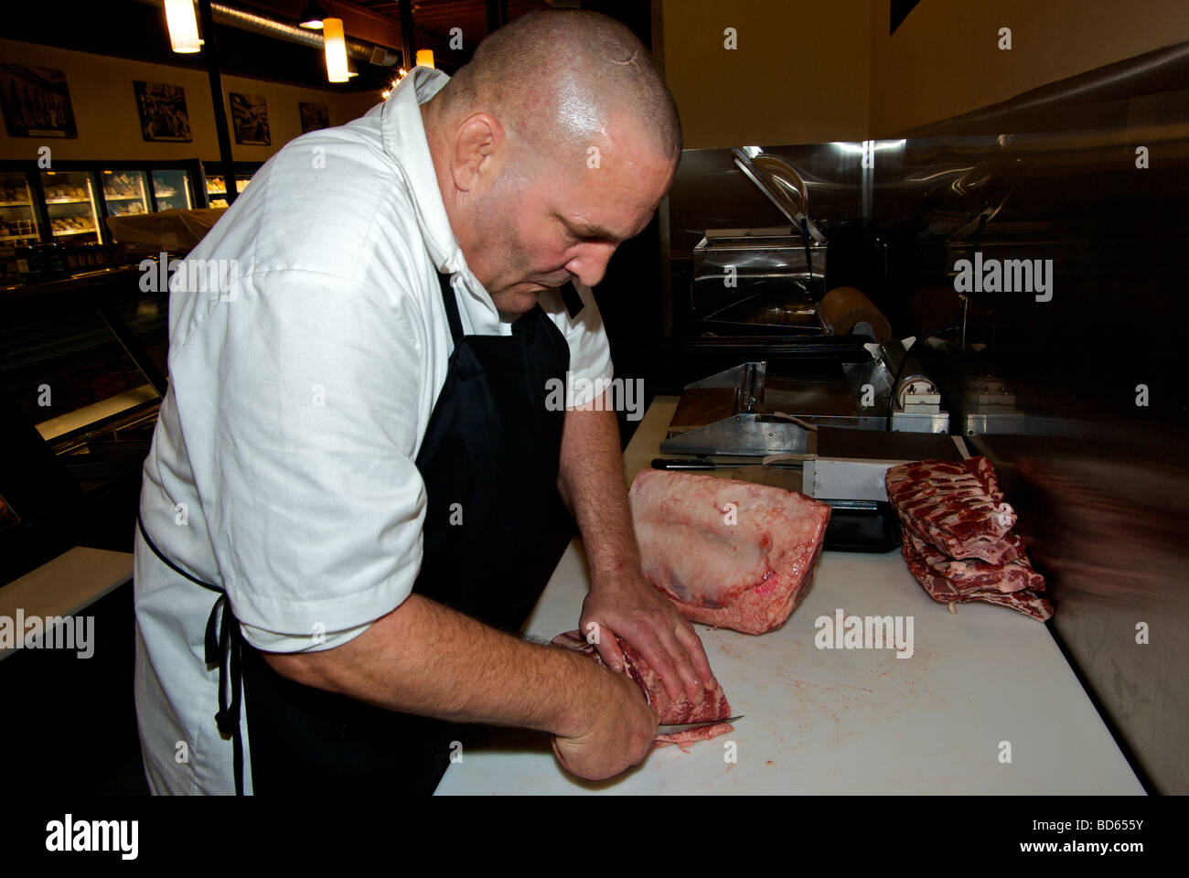 Butcher using narrow blade knife to cut trim beef prime rib roast Stock Photo