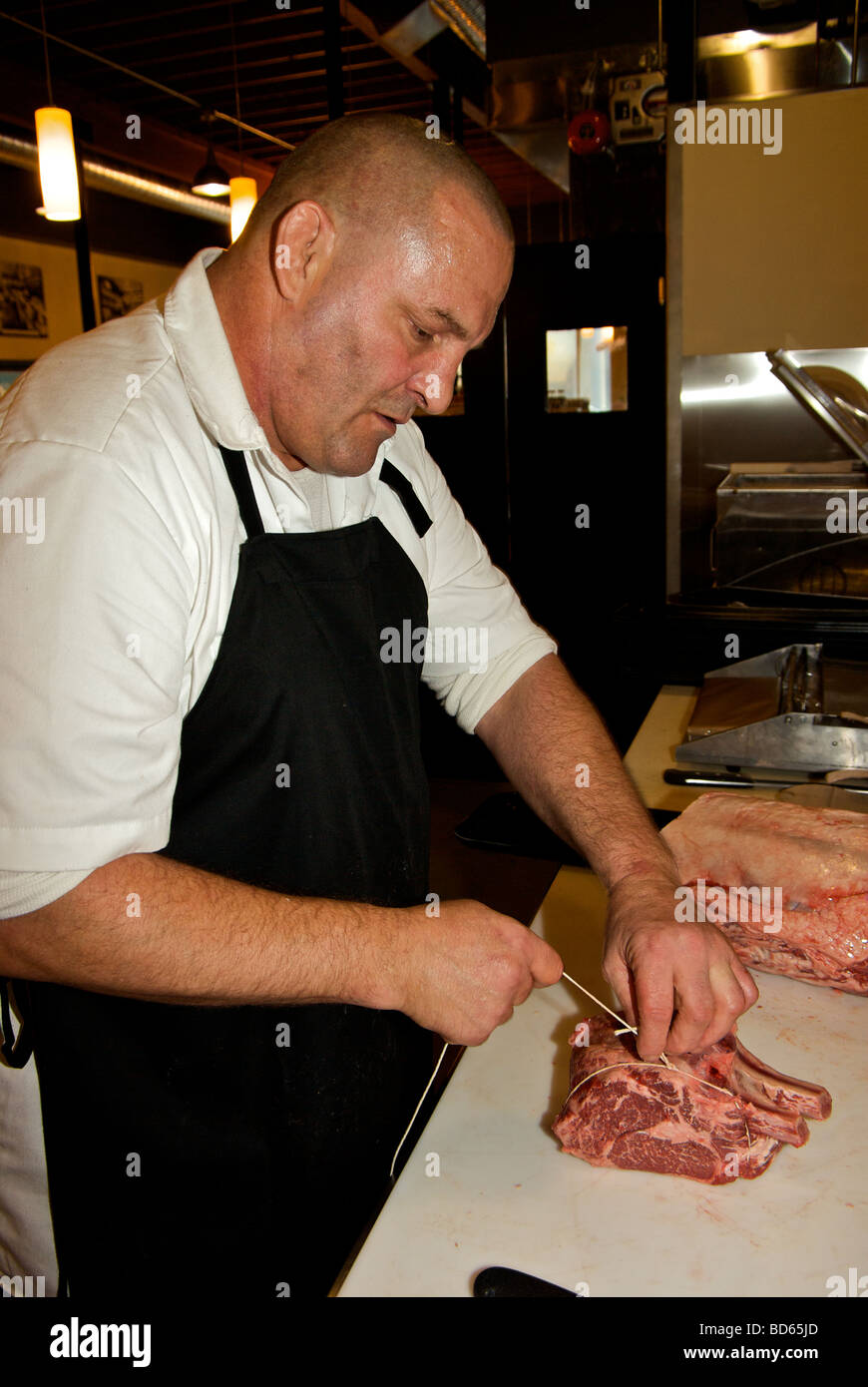 Butcher tying a beef prime rib roast with Frenched bones Stock Photo