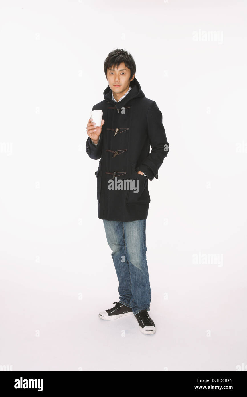 Man in coat holding hot coffee Stock Photo