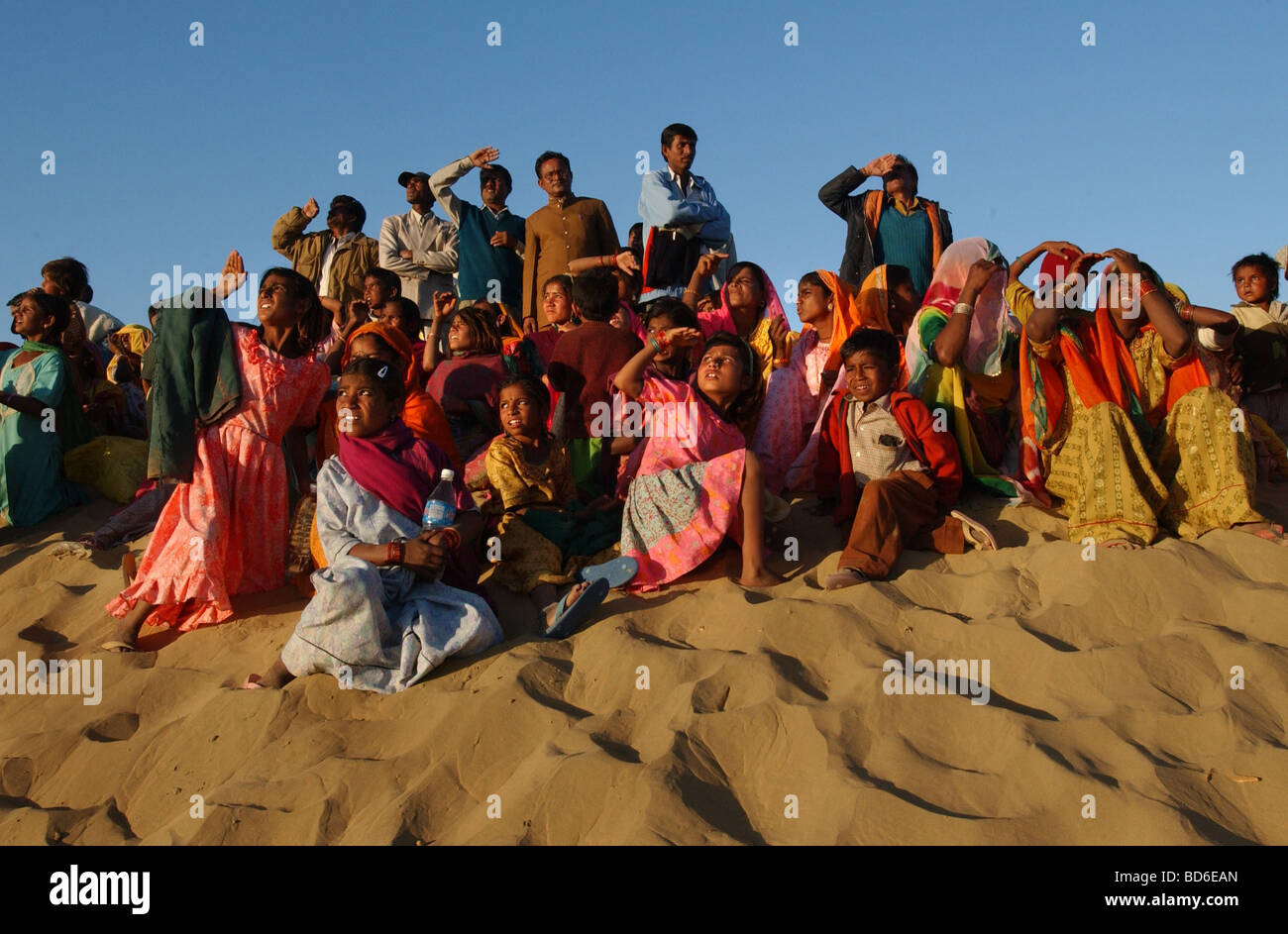 2927309 JAISALMER INDIA FEB 6 2004 Rajasthani tourists watch Indian paratroopers jump out of a helicopter on the last day of Stock Photo