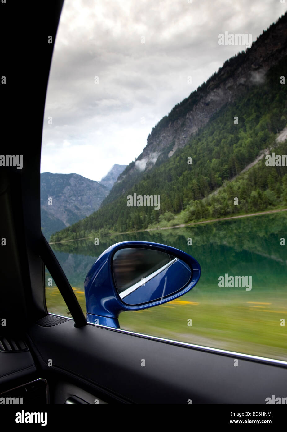 Rear view mirror, driving past alpine lake in a Porsche Panamera S Stock Photo