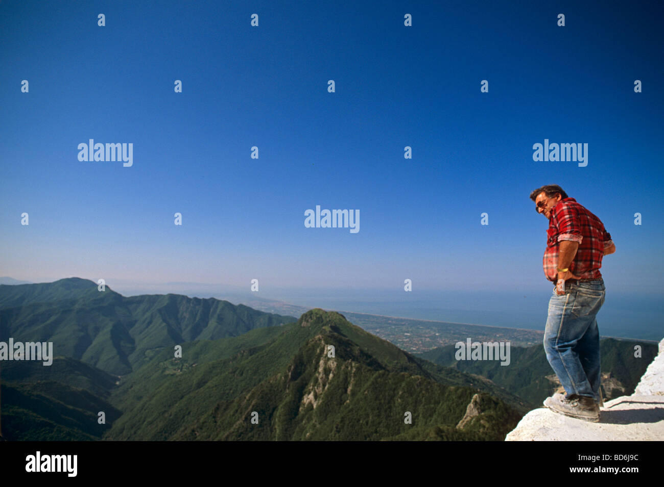 Man standing at the edge of marble quarries at Cervaiole Tuscany Italy Stock Photo