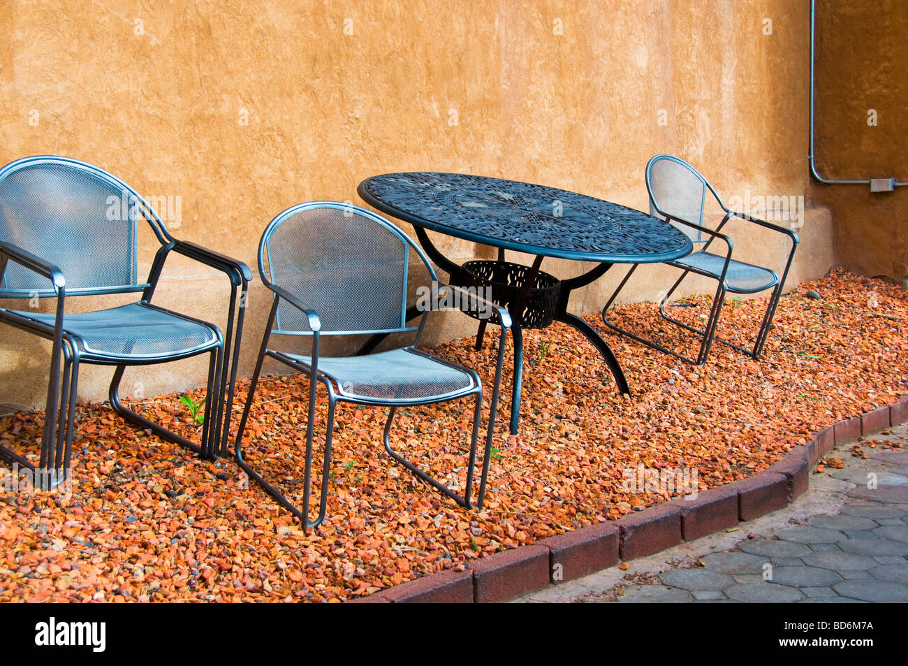 Wrought iron metal patio furniture on slanted gravel yard Stock Photo