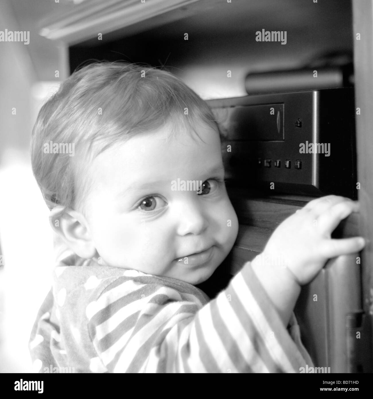 Baby standing up against TV cabinet Stock Photo