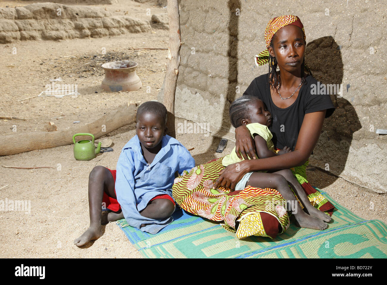 Woman and her two children seated in front of a house, Maroua, Cameroon, Africa Stock Photo
