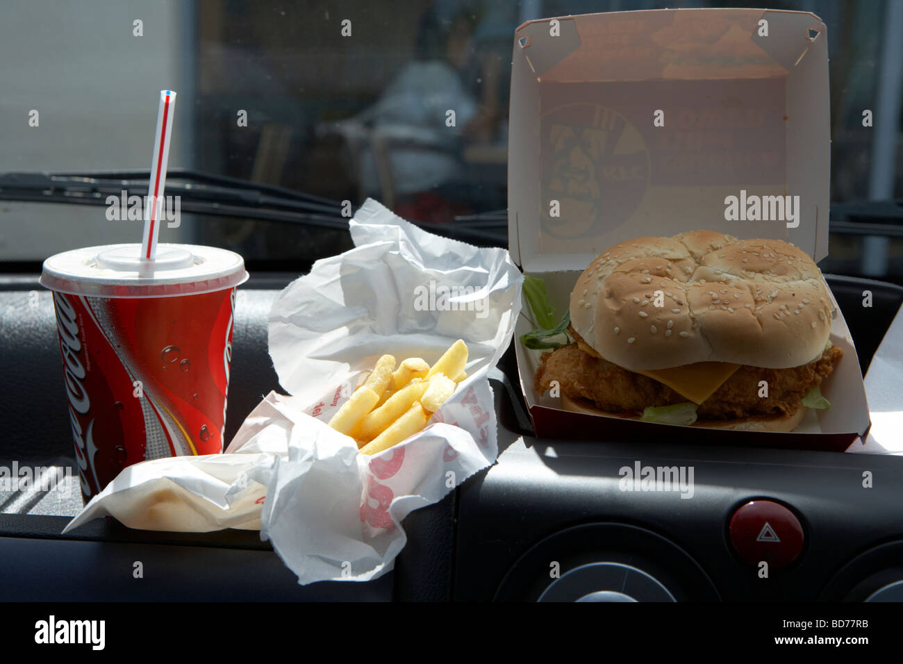 KFC burger fries and coke on the dashboard of a car van having quick fast food lunch Stock Photo