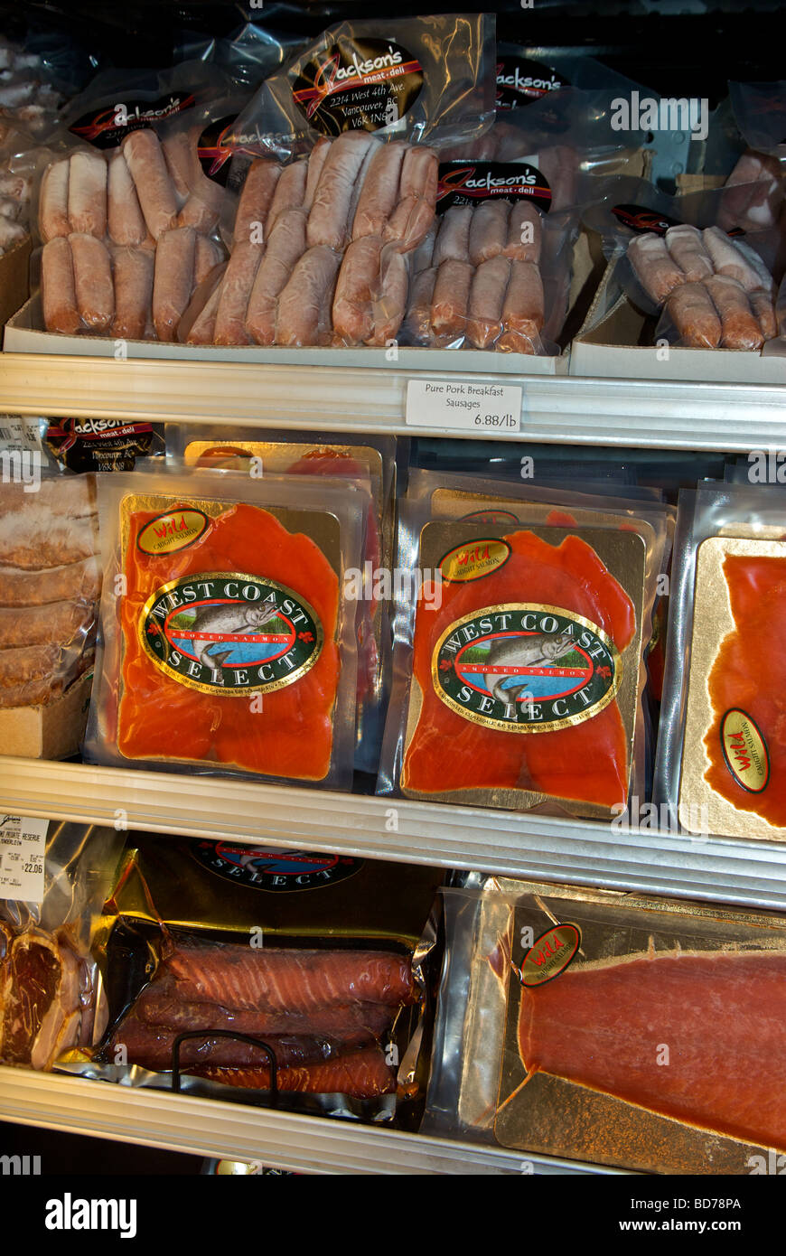 Specialty frozen sausages and smoked salmon in upright freezer display case Stock Photo