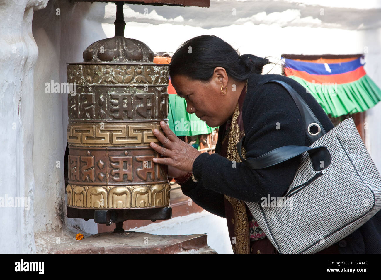 Bodhnath, Nepal.  Buddhist Worshiper Praying at Prayer Wheel. Stock Photo