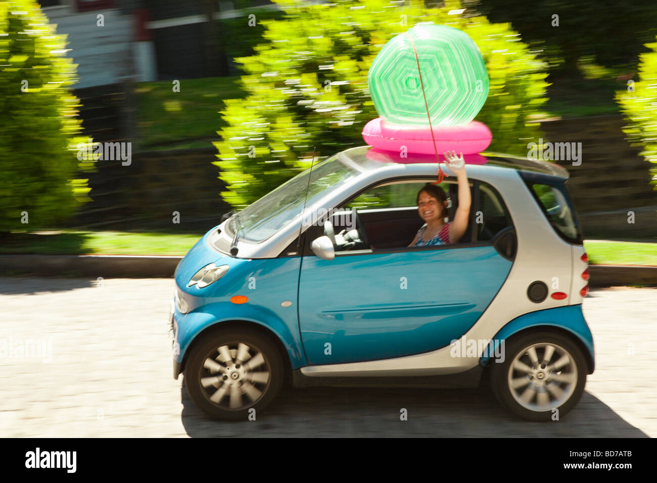 Woman with beach ball on smart car Stock Photo