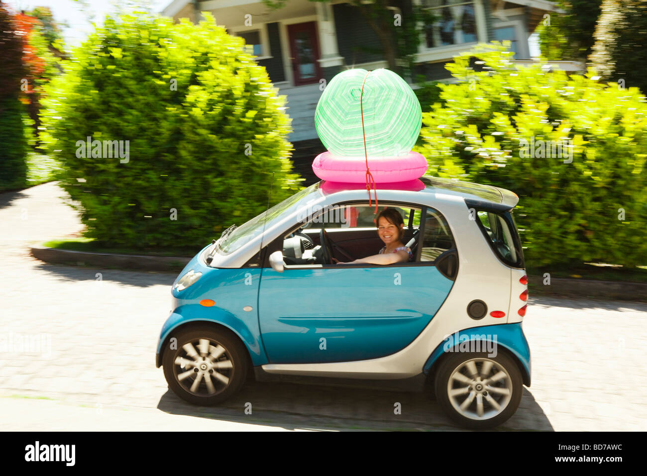 Woman with beach ball on smart car Stock Photo