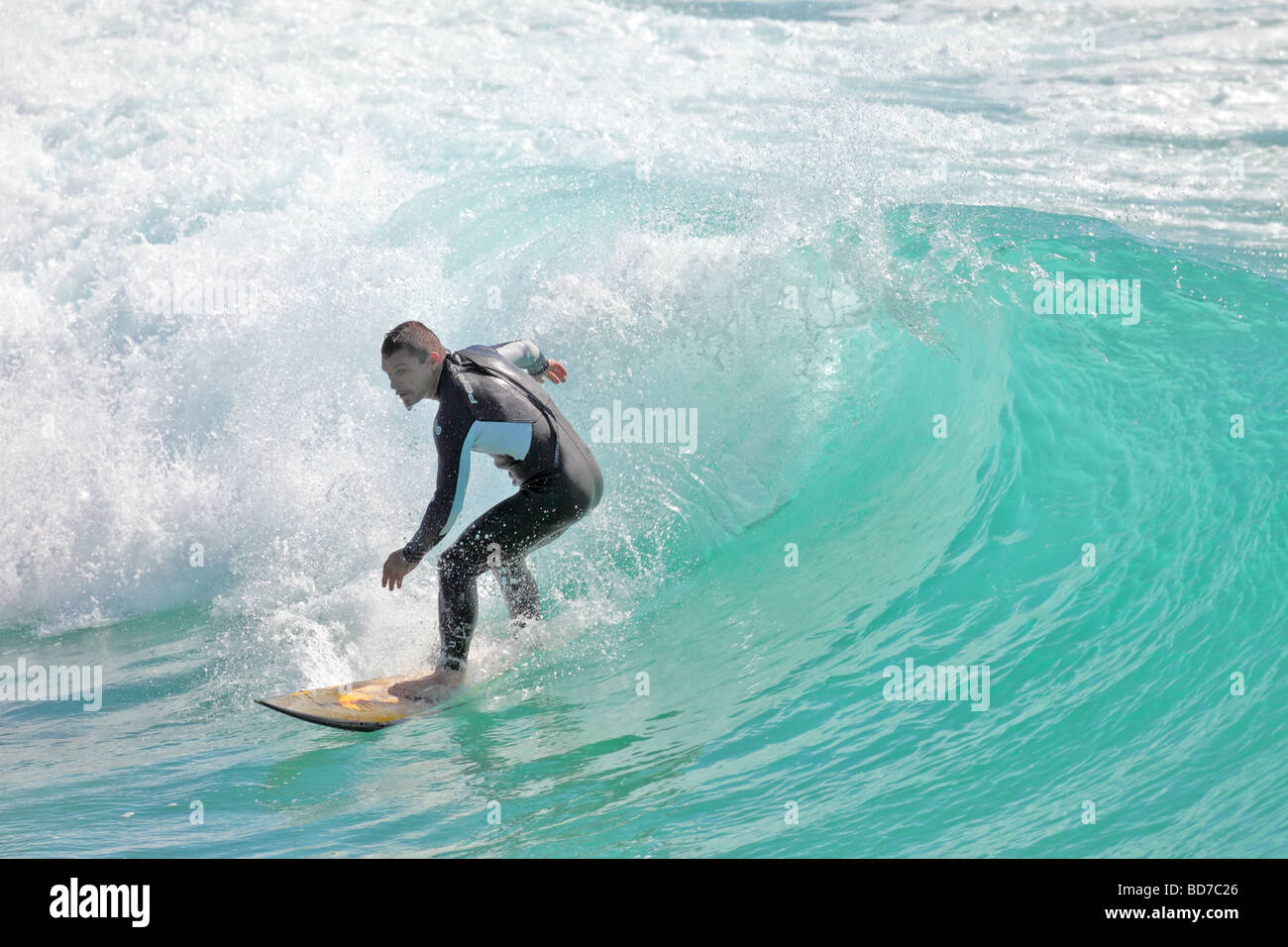 Surfer captures a wave for a ride into the shore late afternoon Stock Photo