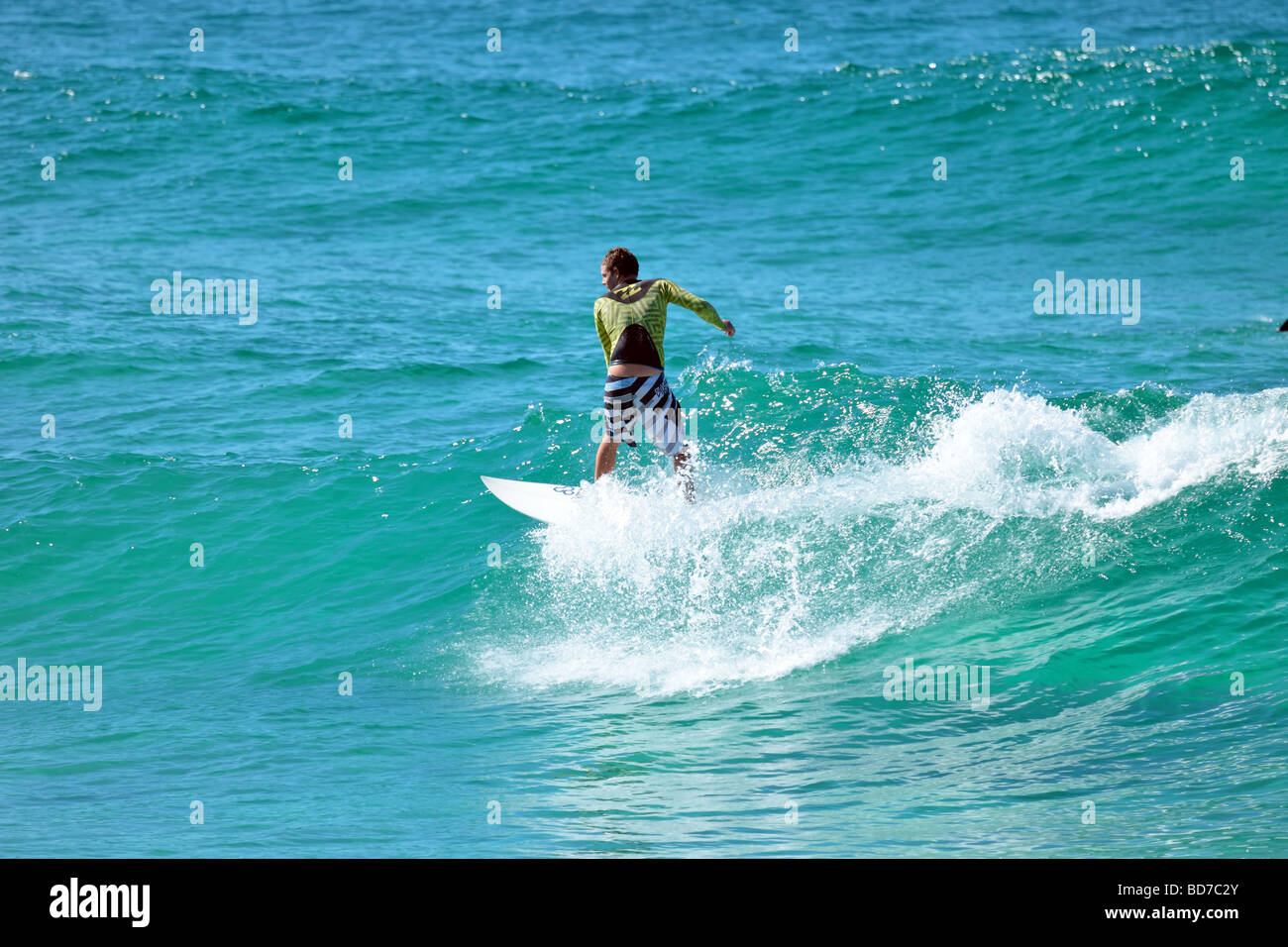 Surfer captures a wave for a ride into the shore late afternoon Stock Photo