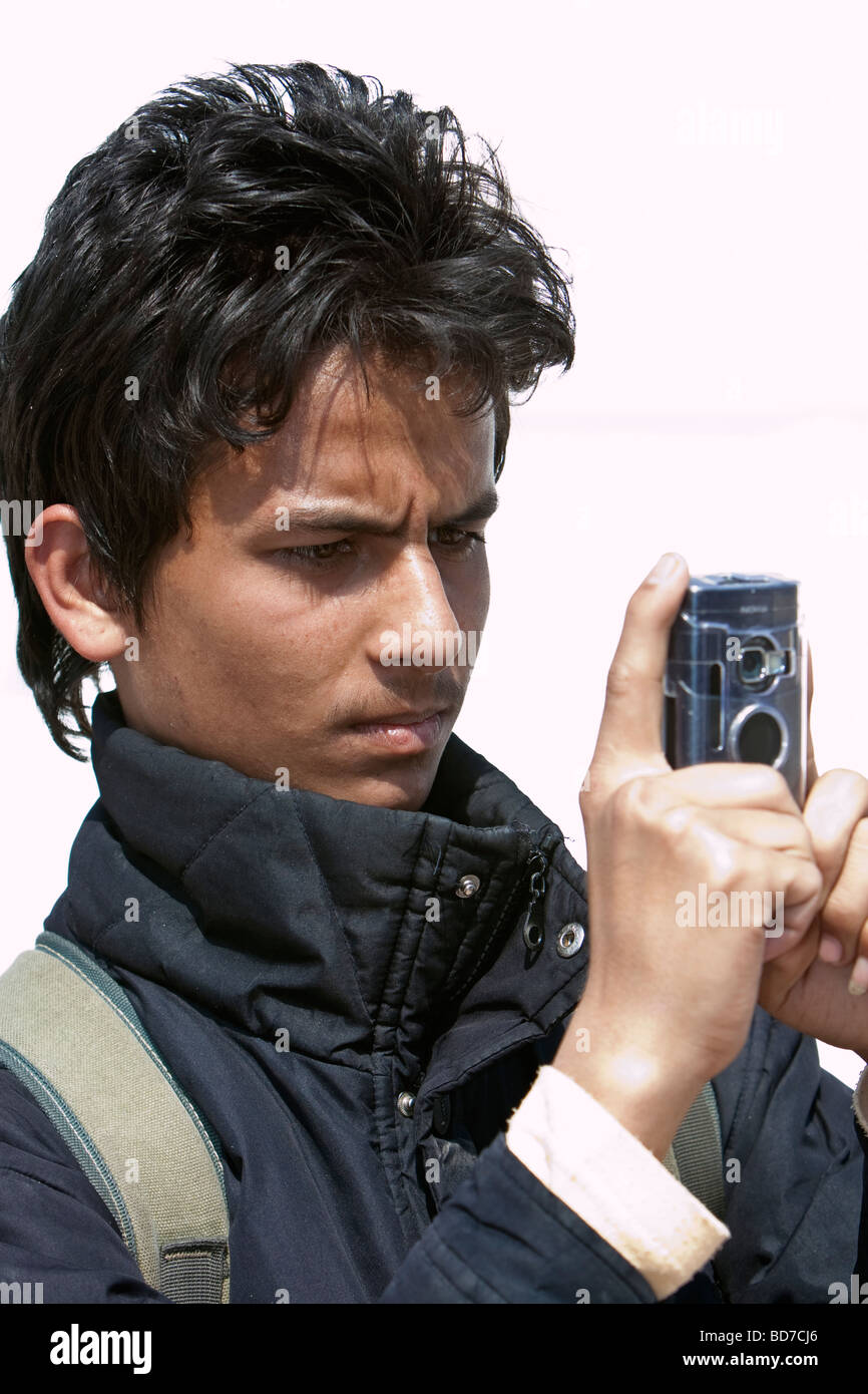 Bodhnath, Nepal.  Young Nepali Man at the Buddhist Stupa of Bodhnath taking Picture with Cell Phone Camera. Stock Photo
