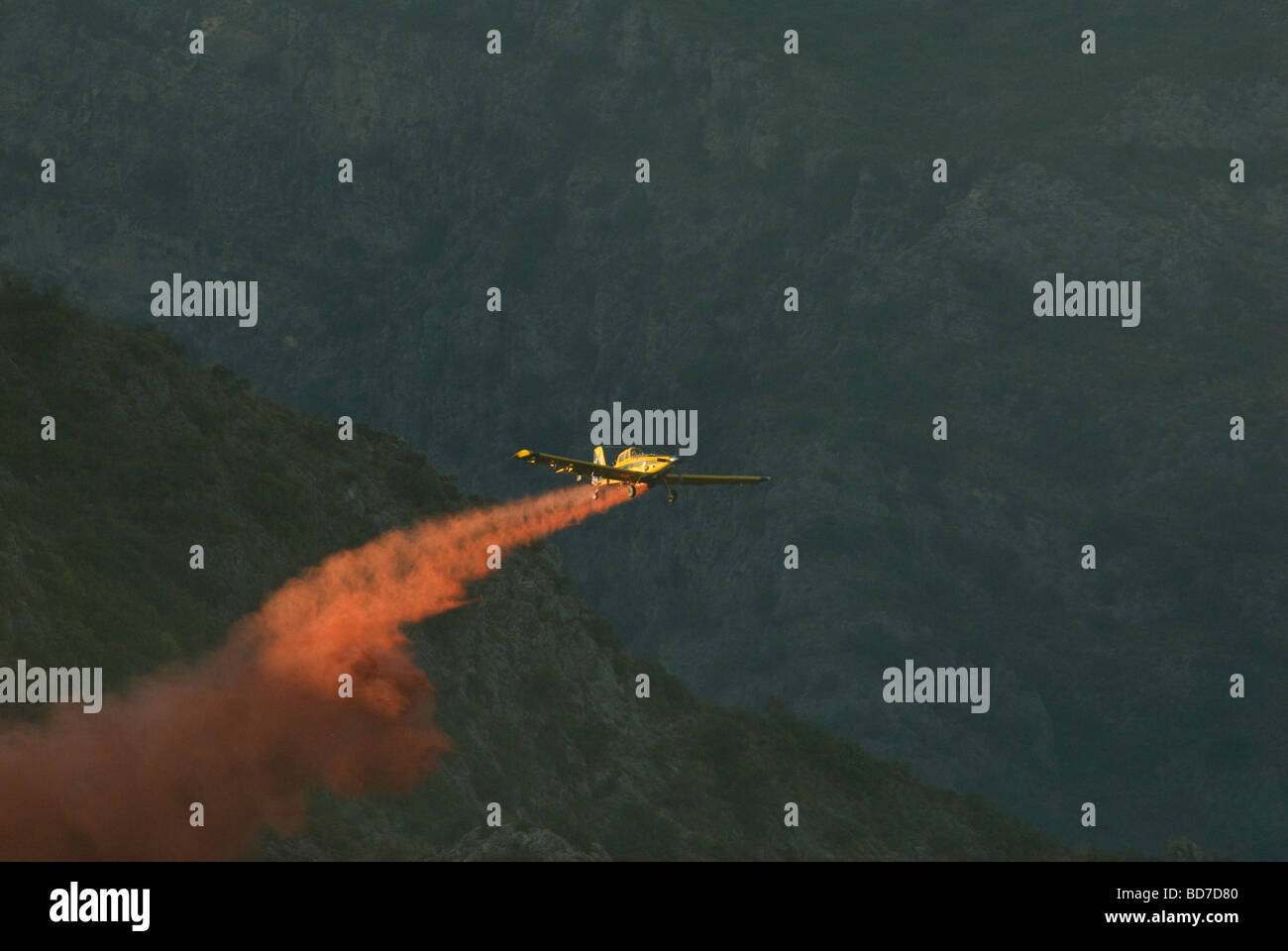 Single engine firefighting plane dropping fire retardant powder on hillside Stock Photo