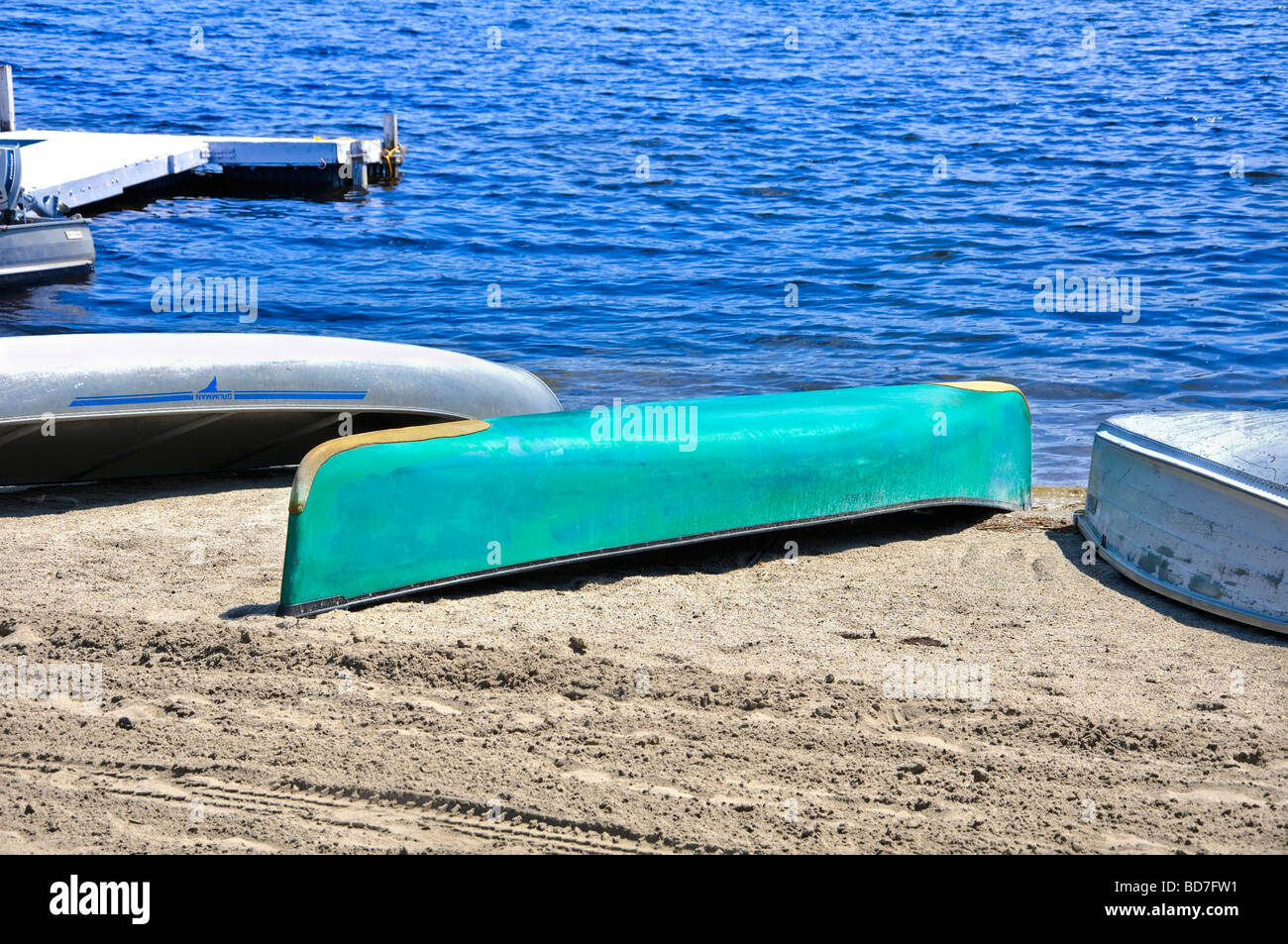 Boat turned upside down drying on a sandy lake shore Stock Photo