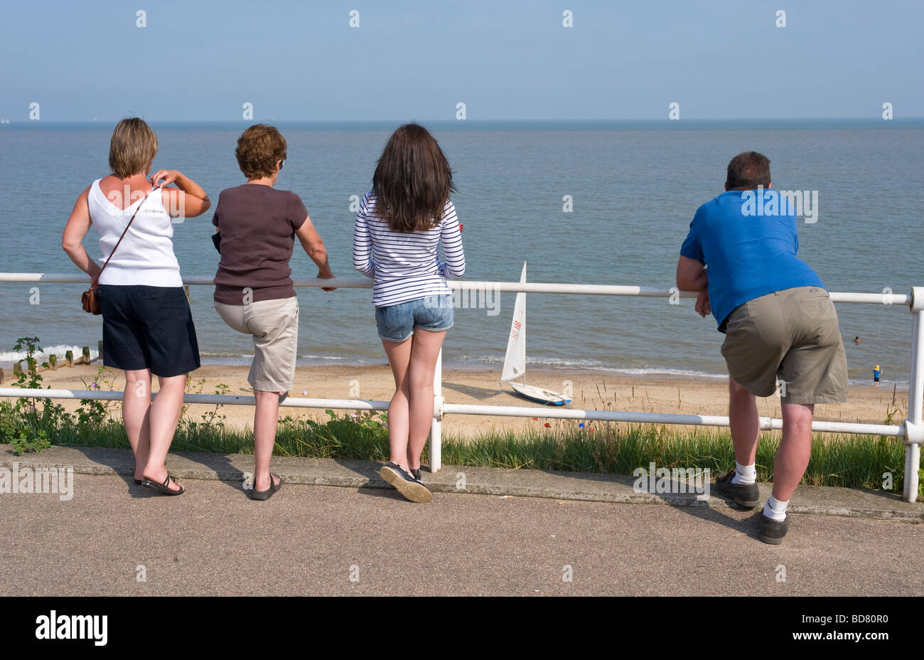people looking out to sea leaning on iron railings southwold suffolk