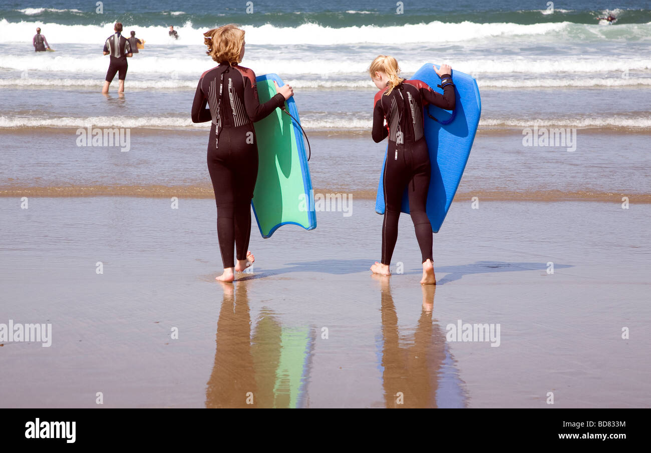 Two girls in wetsuits going bodyboarding in sea Whitesands beach