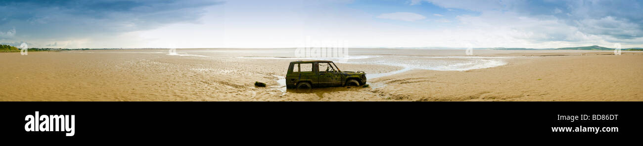Panoramic view of a partially submerged wreck of a car on the beach at Bolton le Sands, Morecambe Bay. UK Stock Photo