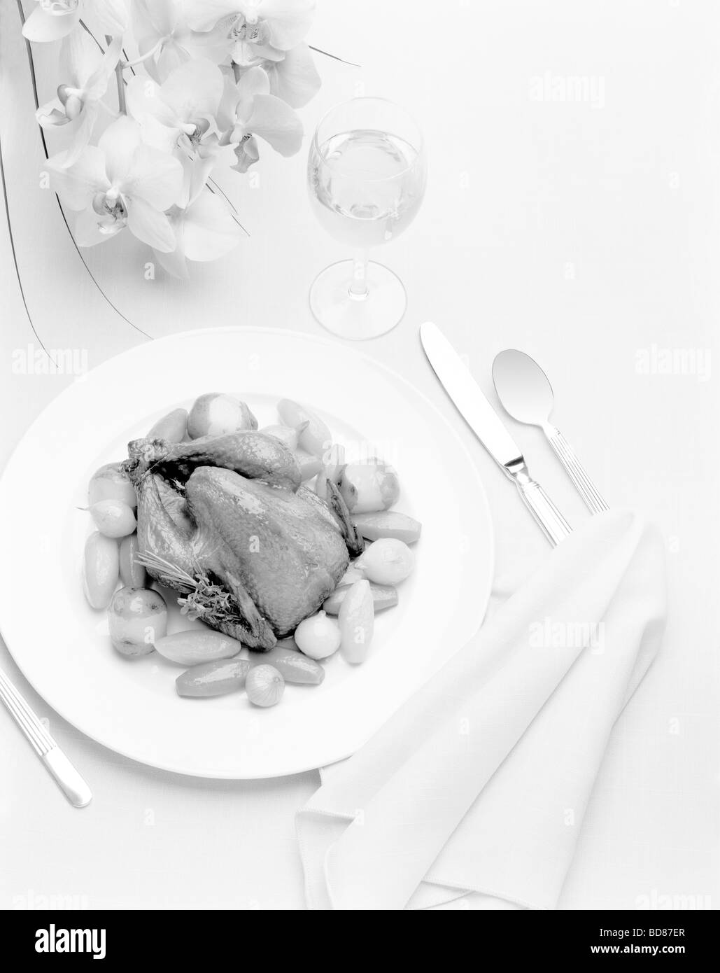 A place setting with a guinea hen and flowers in black and white Stock Photo