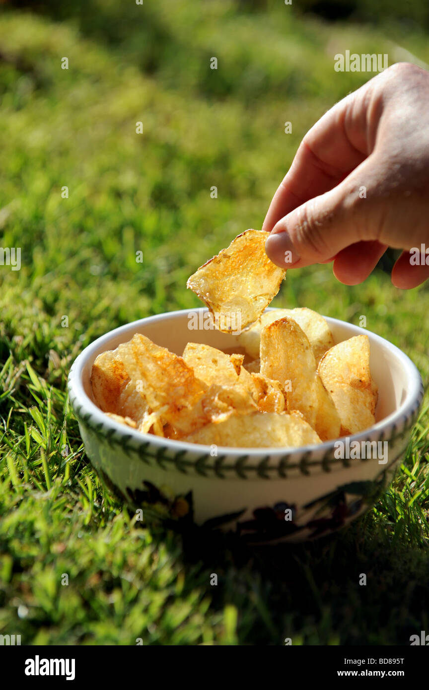 A woman picks up a crisp from a bowl during a summer barbeque Stock Photo