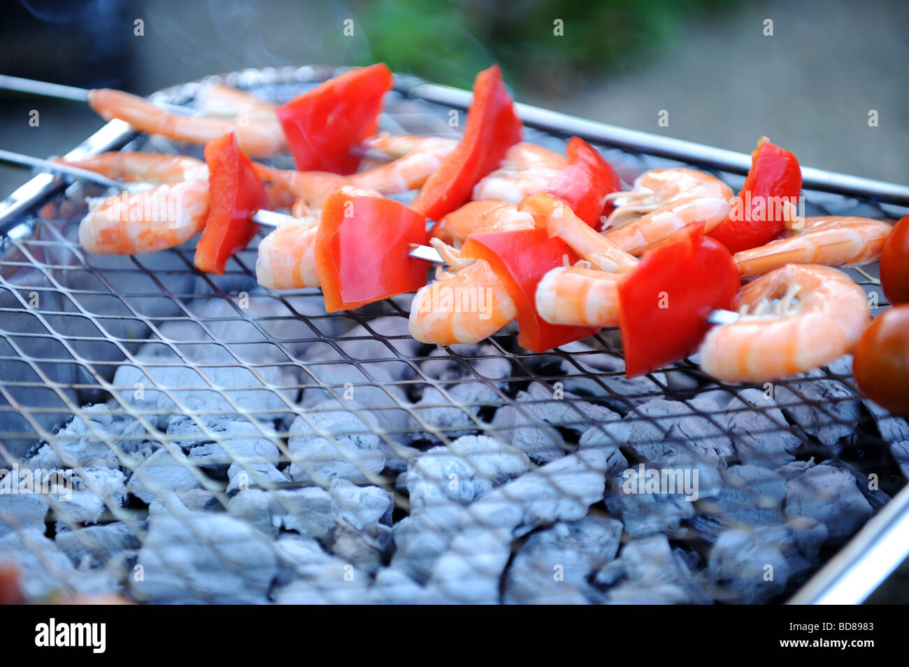 Fresh prawns and red pepper cooking on a disposable barbecue Stock Photo