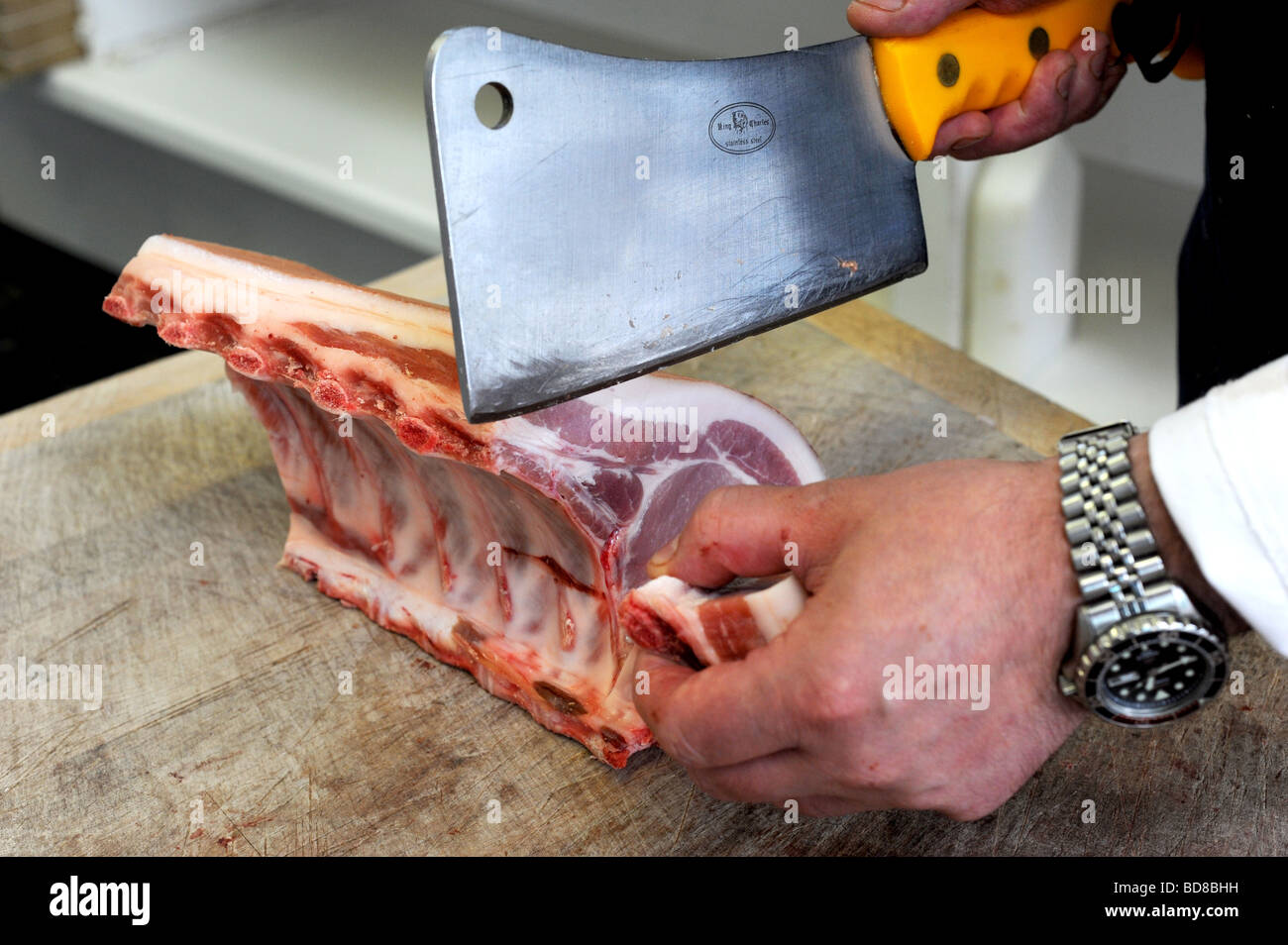 A butcher cuts some pork chops at Bramptons a traditional butchers in Kemp Town Brighton Stock Photo