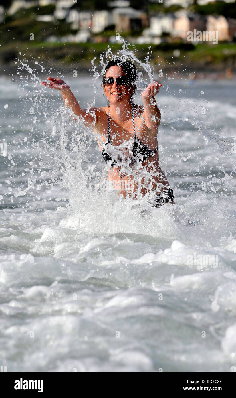 A young woman splashes in surf cooling off in the sea at Woolacombe on the north devon coast Stock Photo