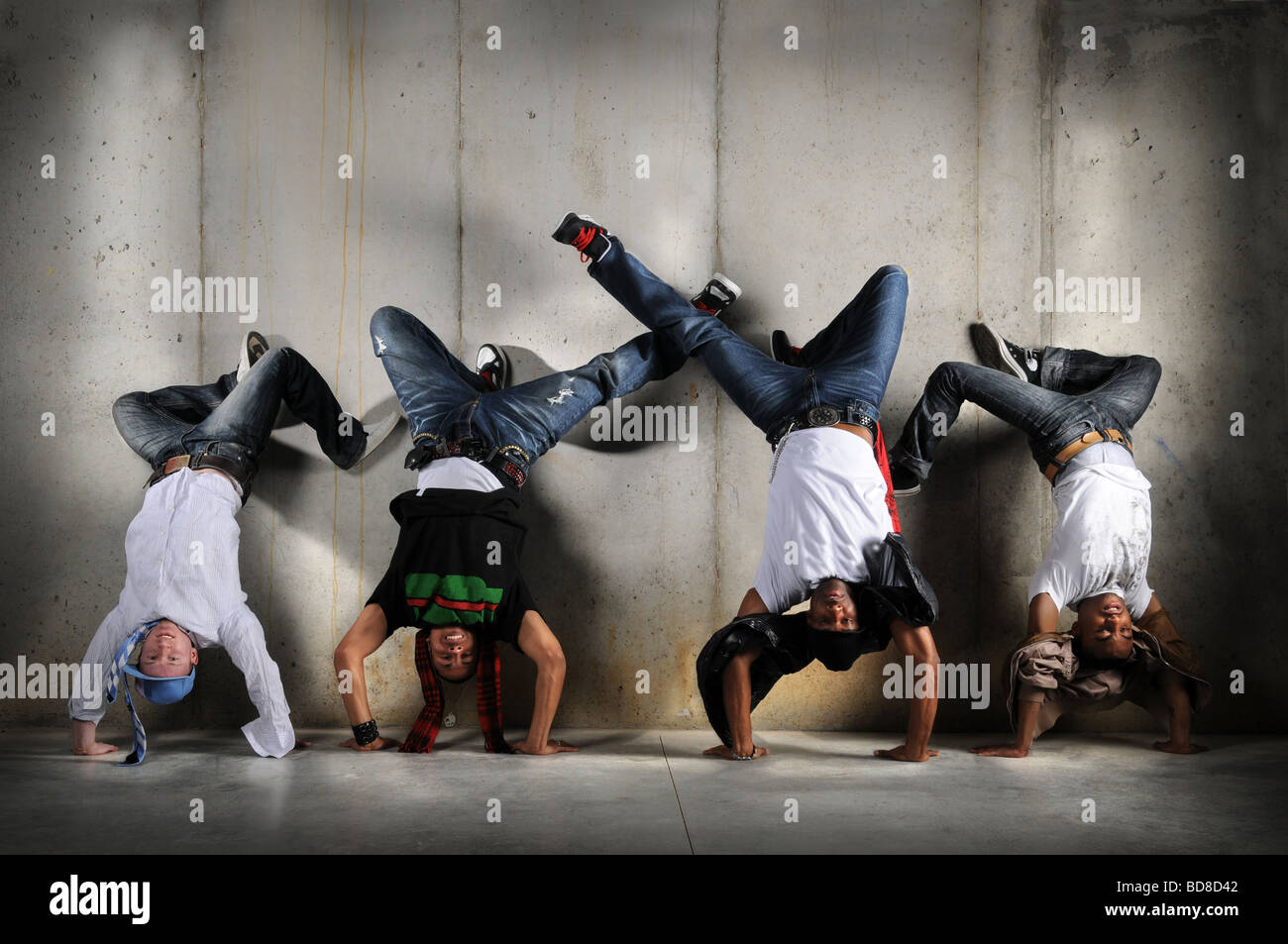 Hip Hop men performing dance with handstand over grunge background Stock Photo