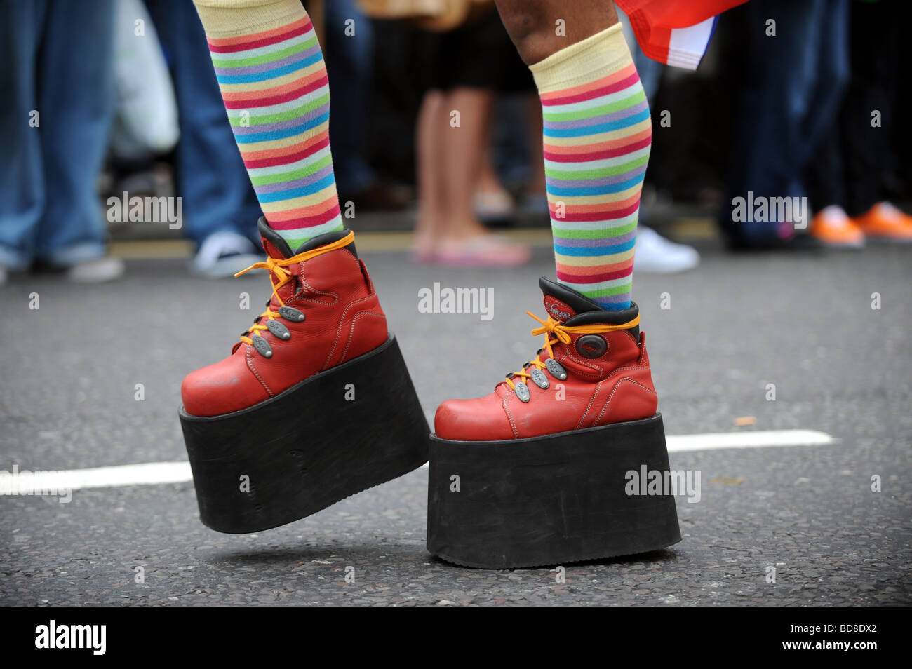 Man wearing massive platform shoes taking part in  Brighton Pride procession many in fancy dress or outrageous outfits Stock Photo