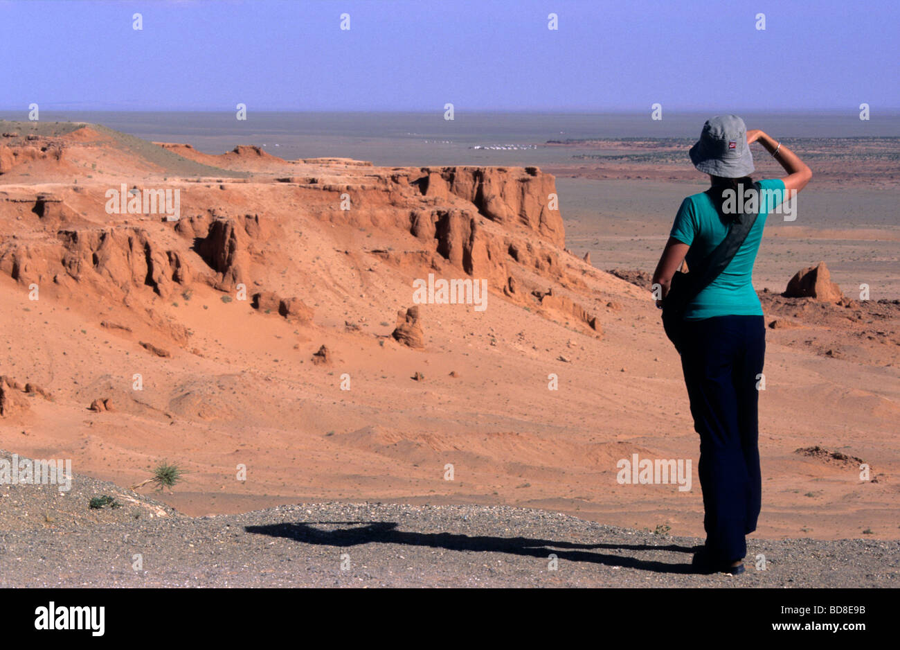 Tourist watching the panorama at the red earth of Bayanzag flaming cliffs, aka dinosaur cemetery, Gobi Desert, Mongolia Stock Photo