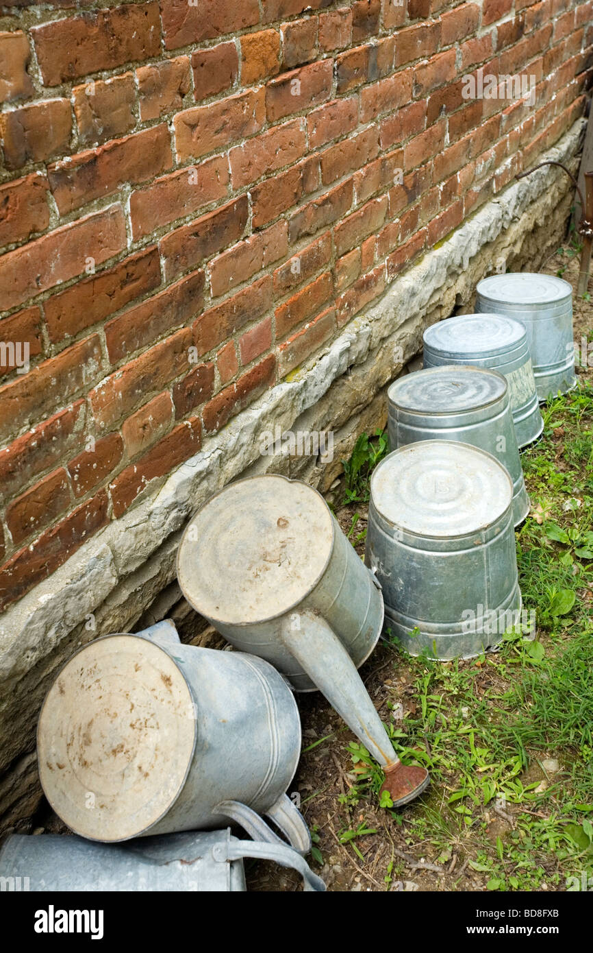 Buckets and watering pails along a wall Stock Photo