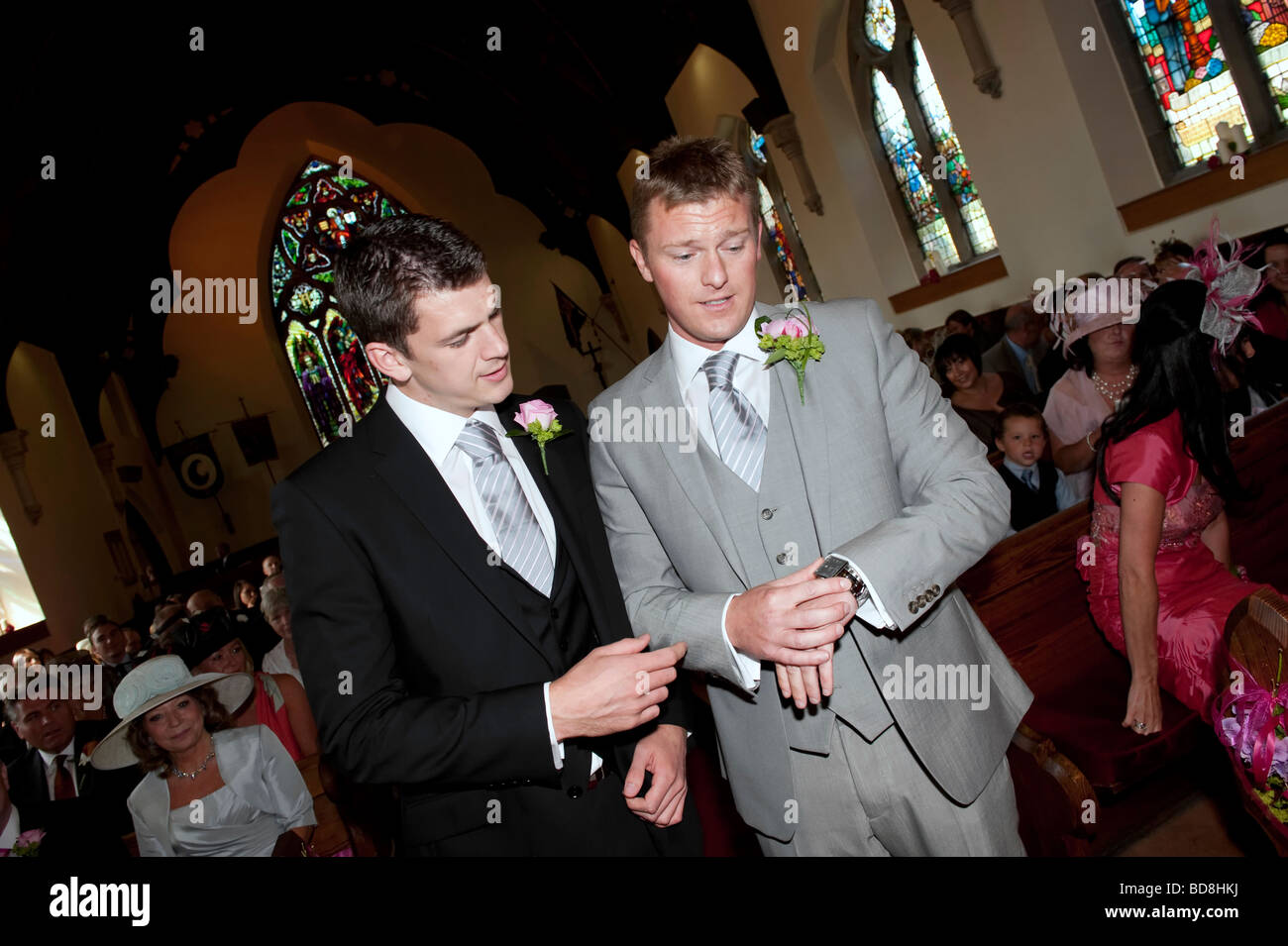 Groom and best man check the time inside church Stock Photo