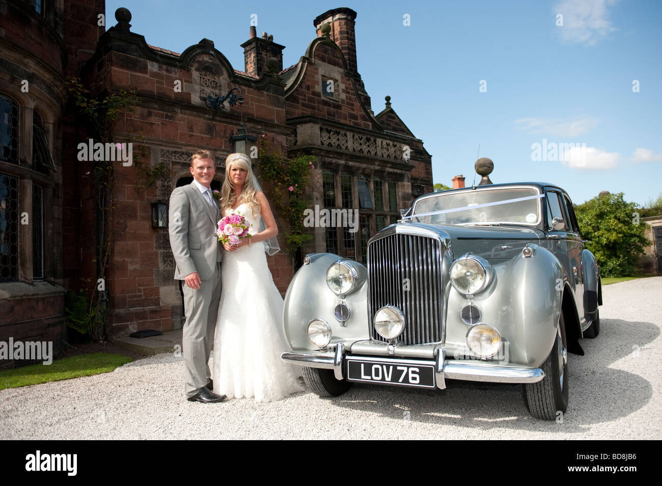 Bride and Groom with old Bentley outside large country house Stock Photo