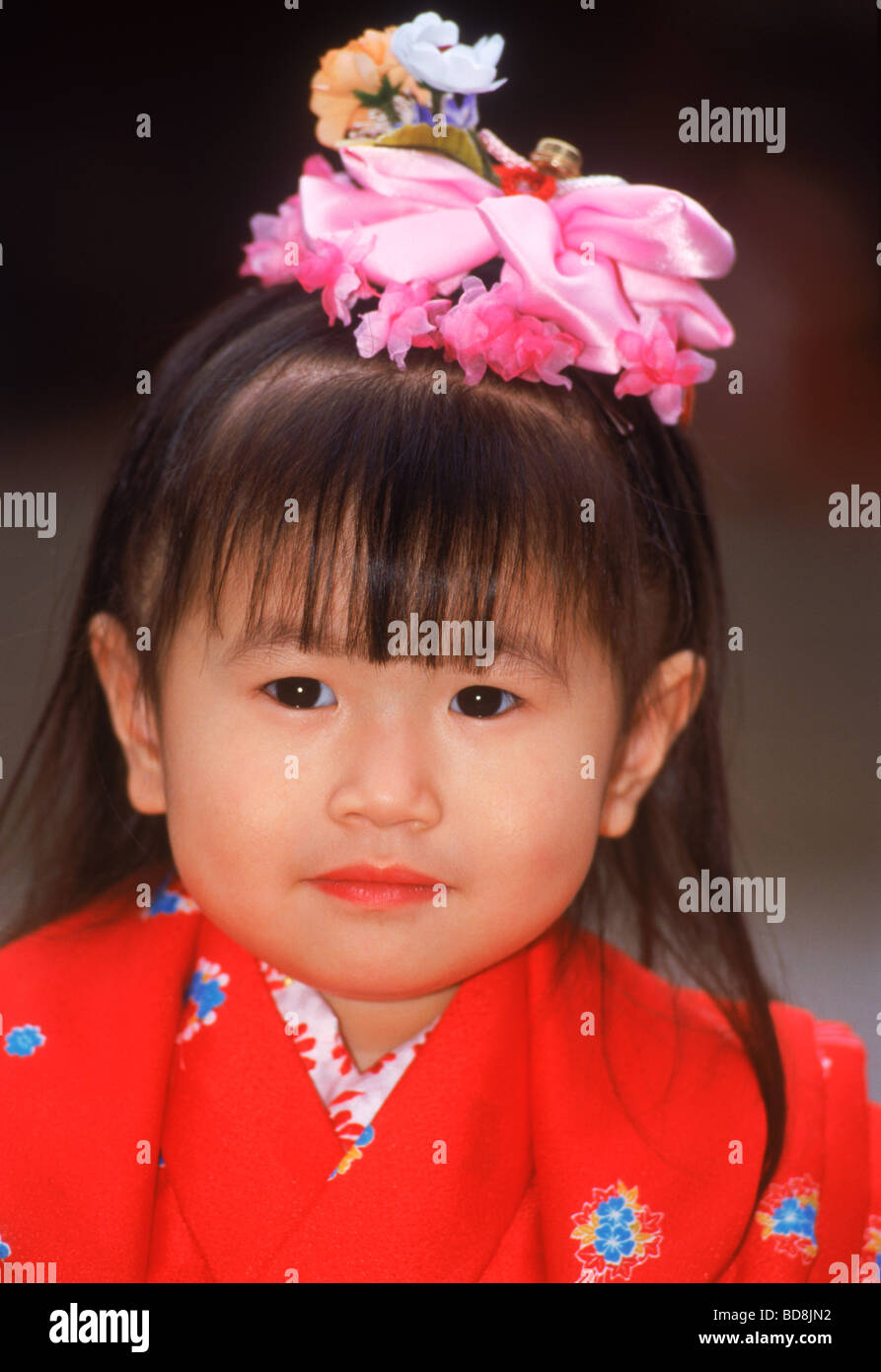Japanese girl in red kimono robe with flower hair decoration Stock Photo