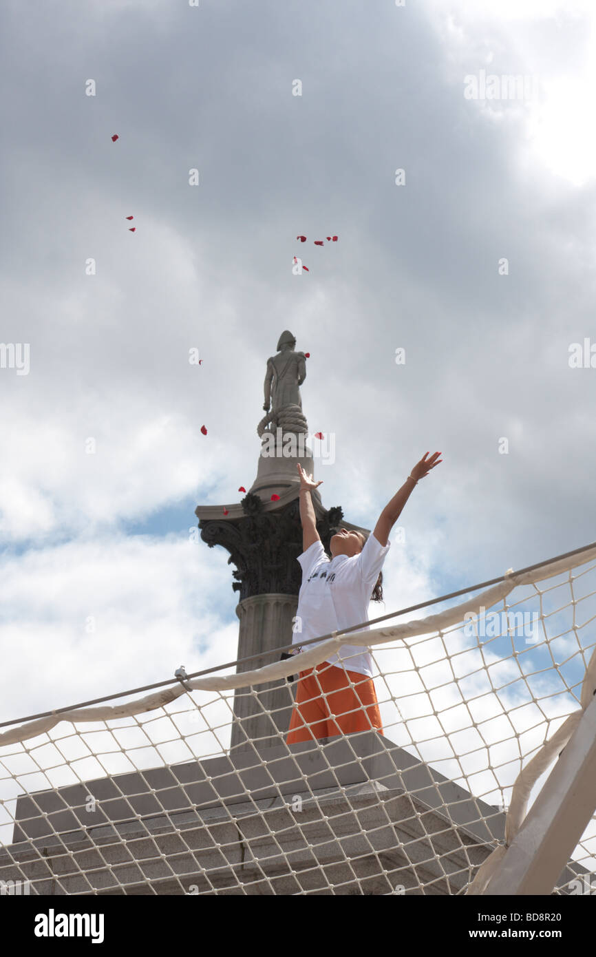 Female participant in Antony Gormley s "One and other" event on the fourth plinth in Trafalgar square throwing petals into the a Stock Photo