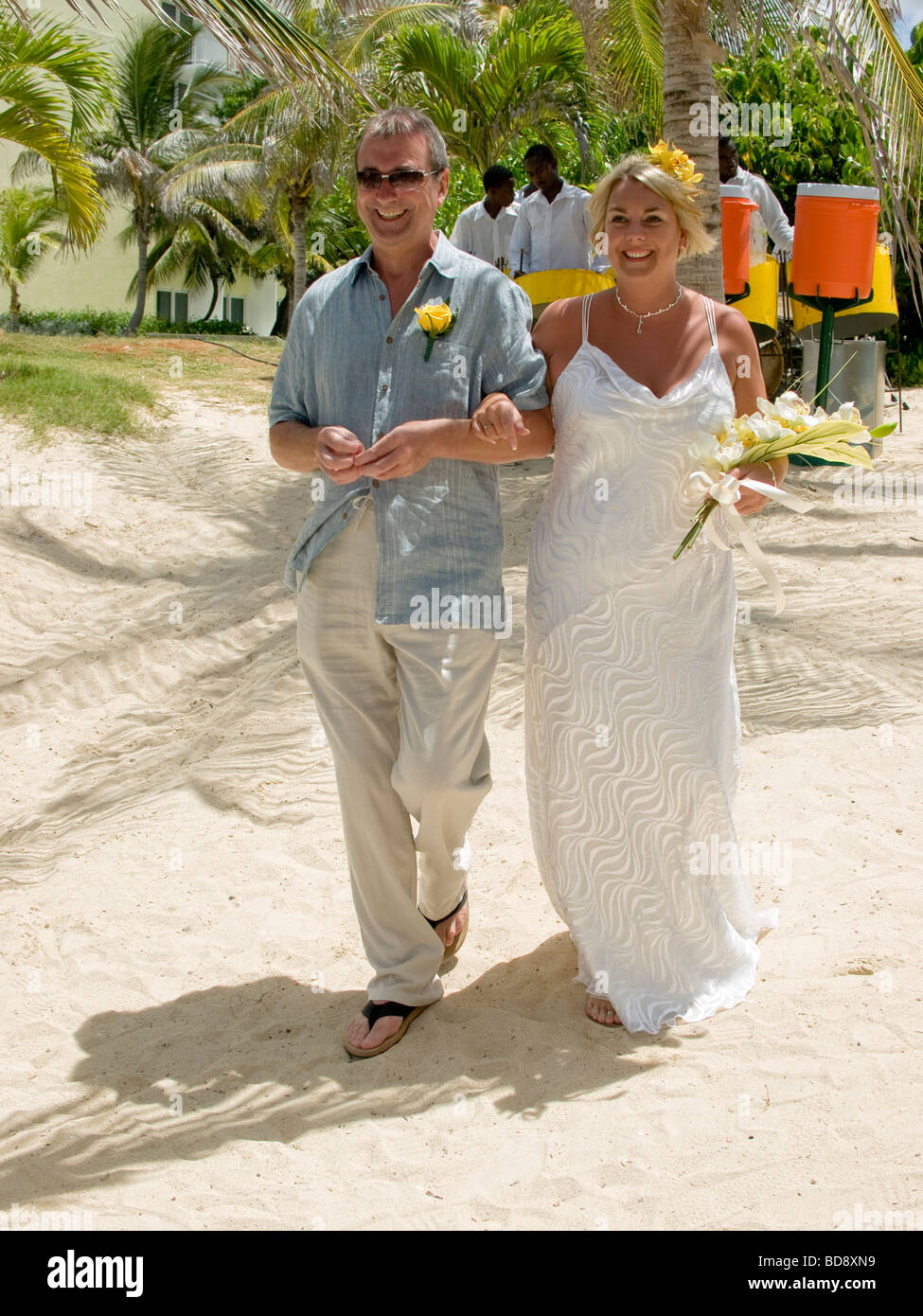A Bride And Her Father Walk Arm In Arm Down To A Tropical