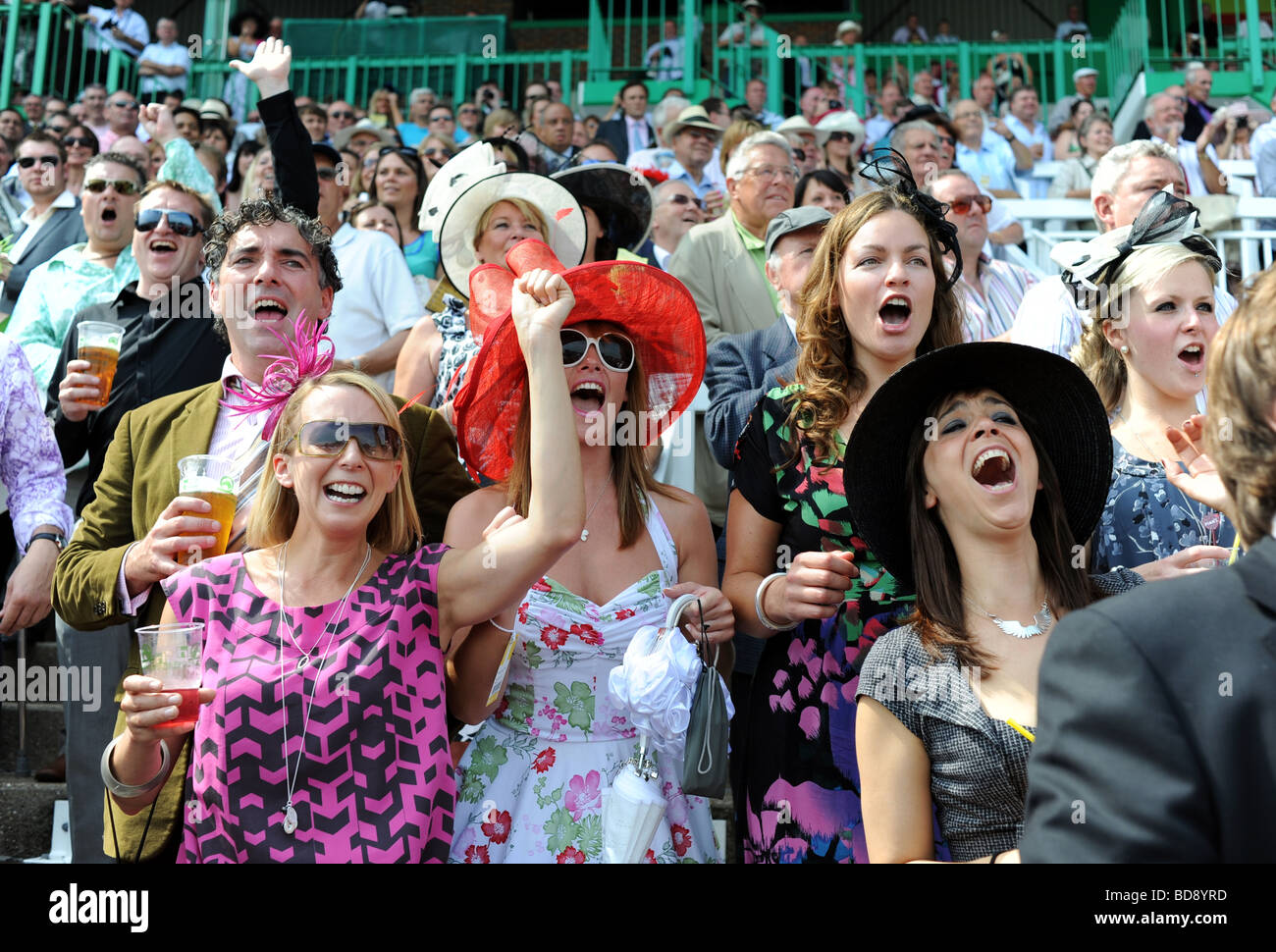 Racegoers in glamorous outfits and hats cheer on the runners and riders at Brighton Races Ladies Day Stock Photo
