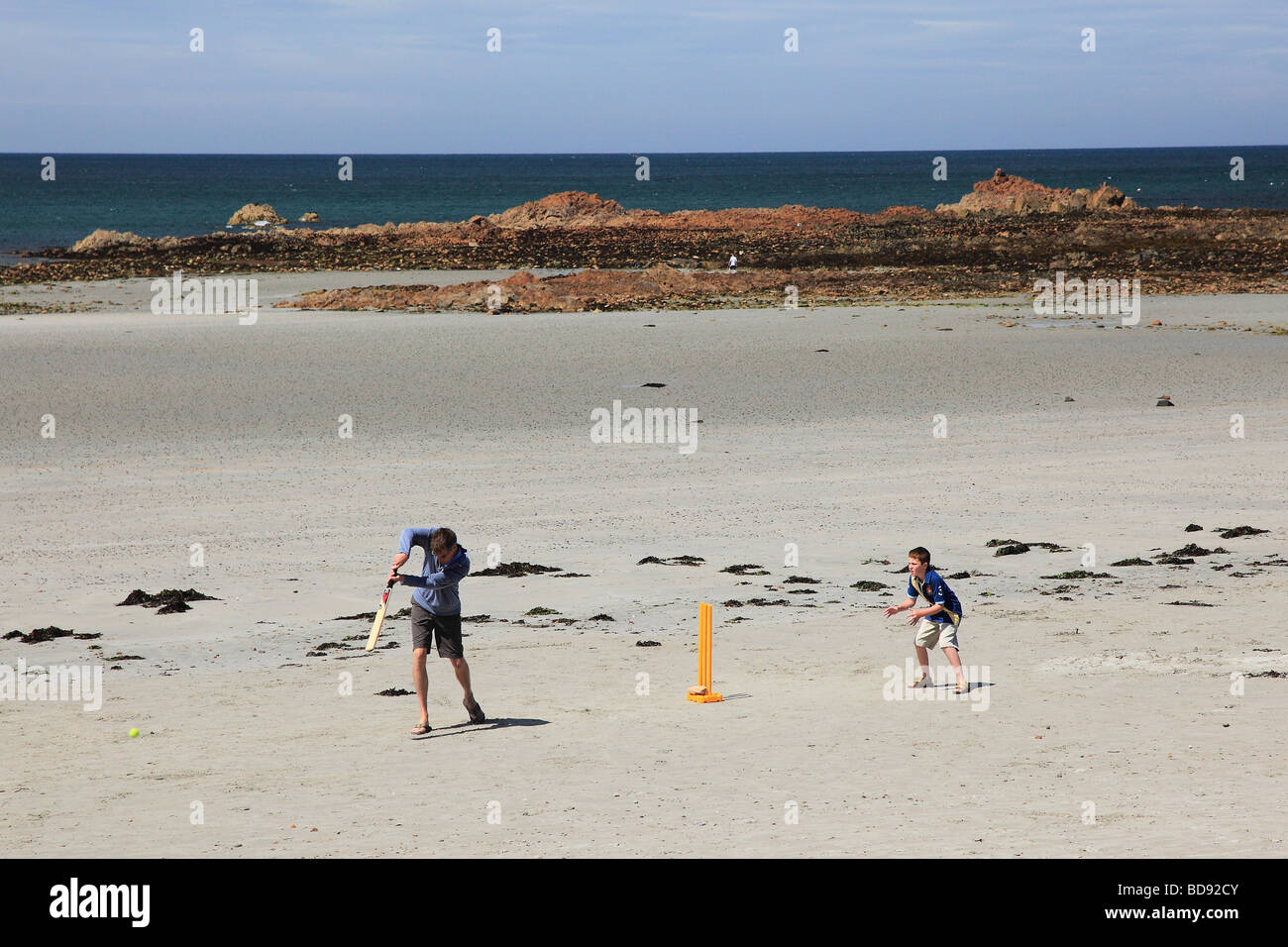 Man and a boy playing cricket on the beach of Grandes Rocques, Guernsey, Channel Islands Stock Photo