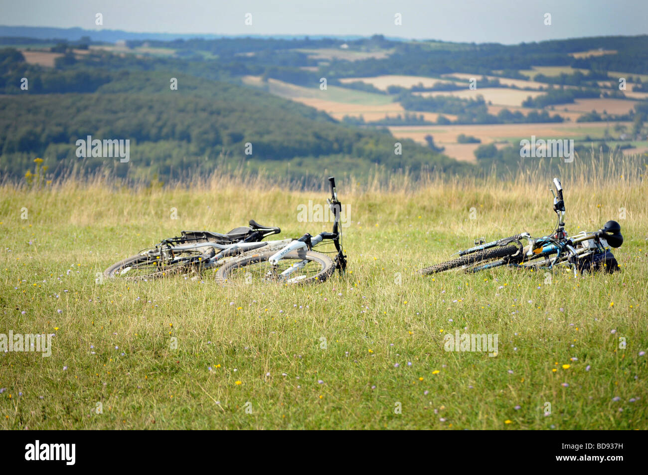 Royalty free photograph of two mountain bikes laying on the grass on top of a hill in the British countryside UK Stock Photo