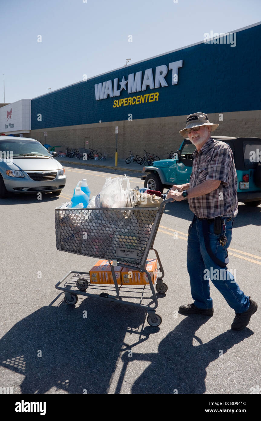 older man with shopping cart full of items in parking lot of Wal Mart