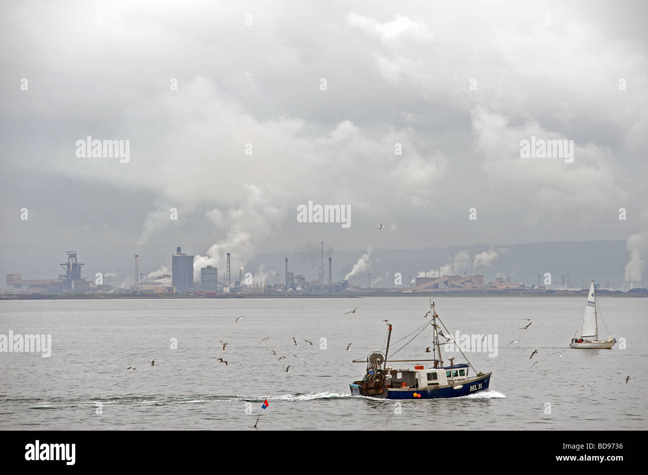Fishing boat sailing into the river Tees past the Corus steel plant at Redcar, Cleveland, UK. Stock Photo