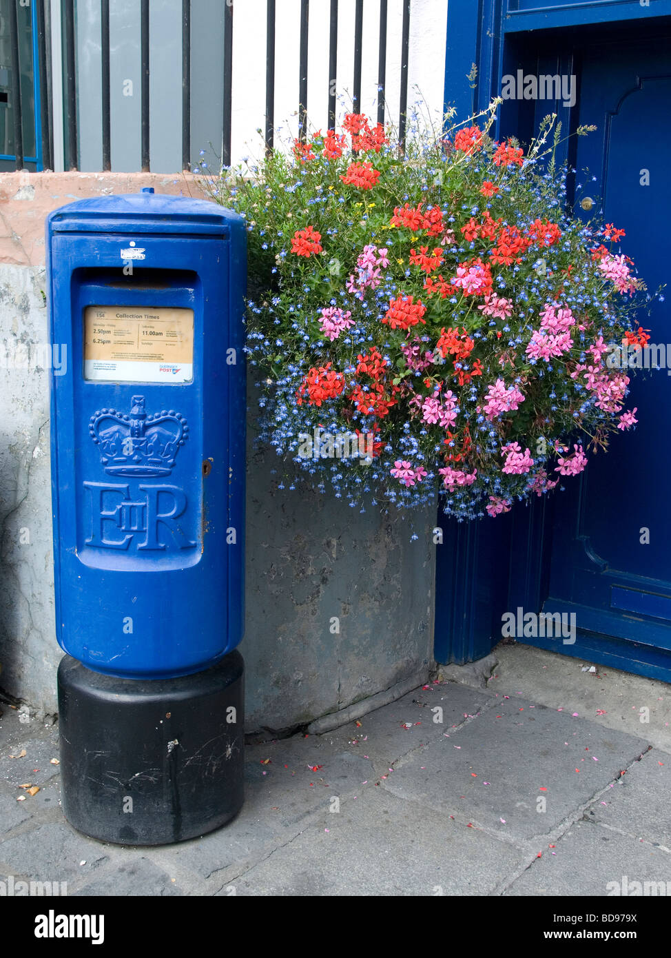 A blue post box with a large floral hanging basket in St Peter Port Guernsey Channel Islands Stock Photo