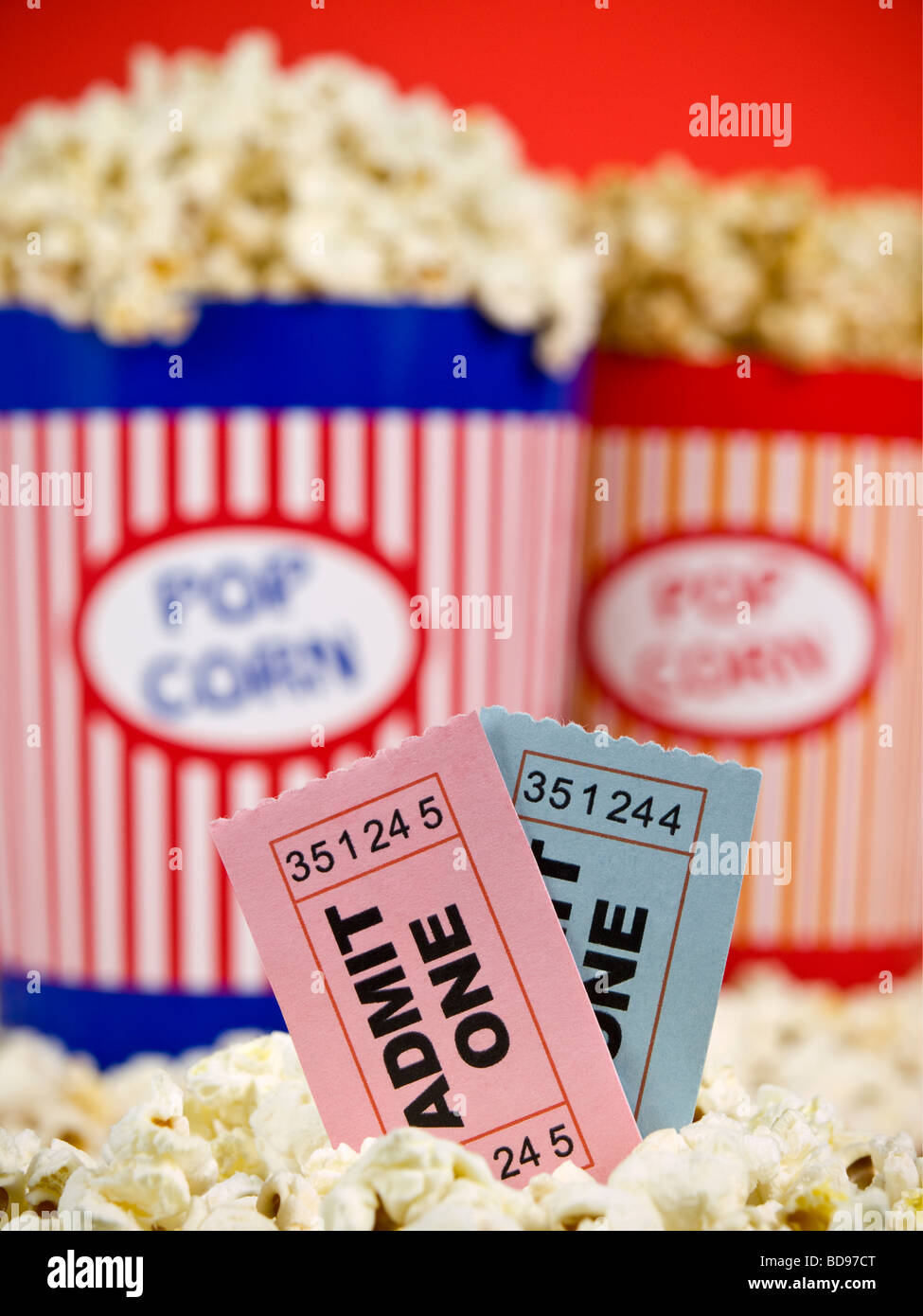 Two popcorn buckets over a red background. Movie stubs sitting over the popcorn. Stock Photo