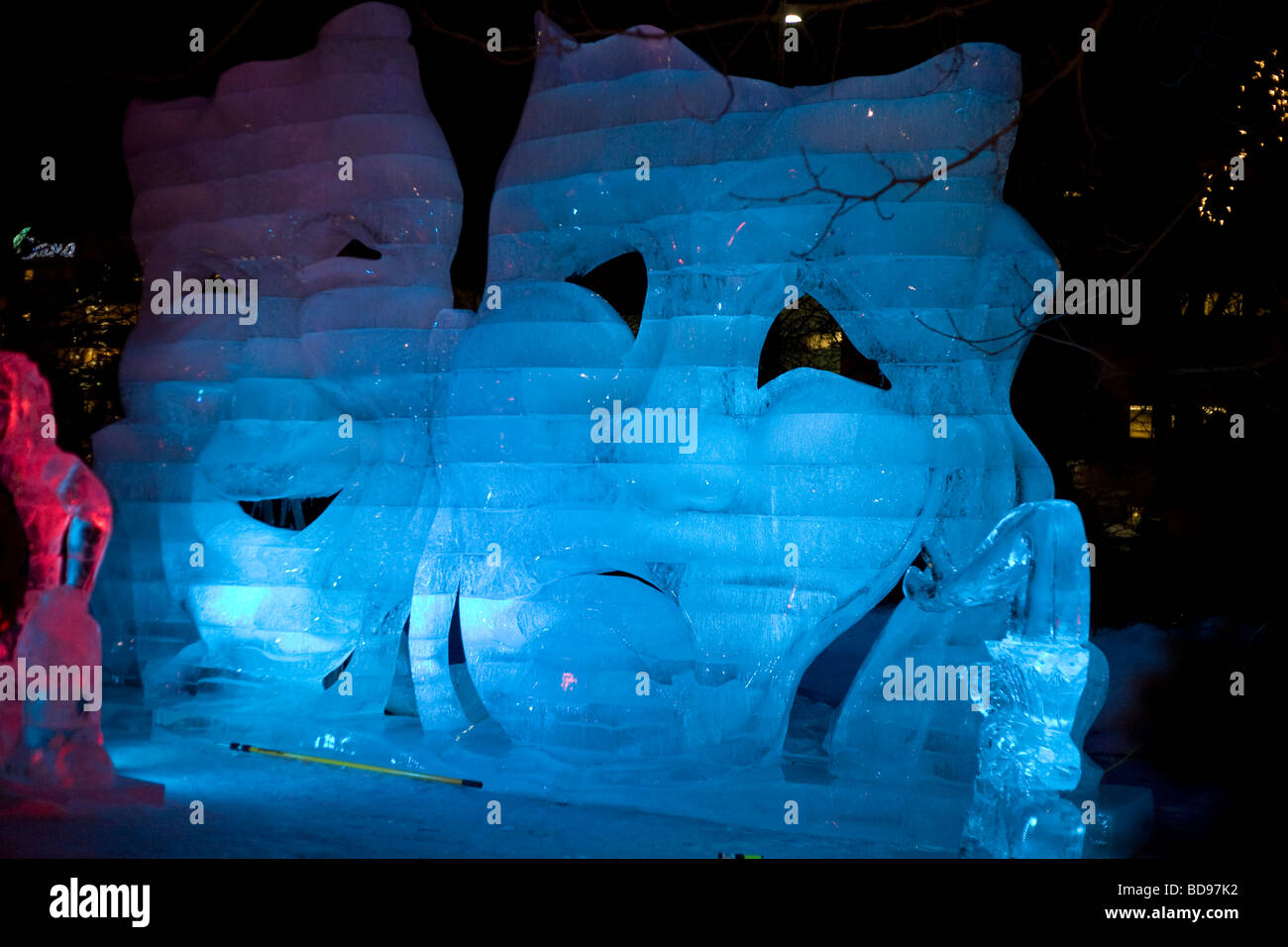 Comedy and Tragedy in Ice. An ice sculpture of the famous masks at night, backlit with blue LEDs. Stock Photo