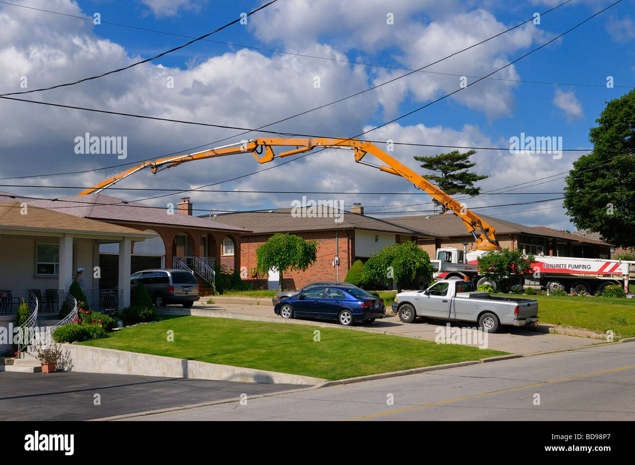 Concrete pumping truck reaching over a house to pour in back yard Toronto Stock Photo