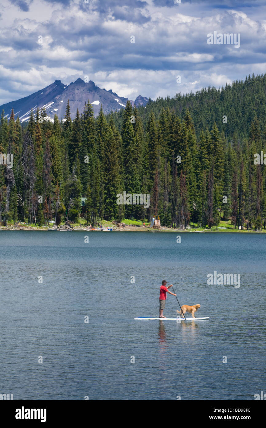 Man and golden retriever on Elk Lake and Three Sisters Mountains in the Cascades of central Oregon Stock Photo