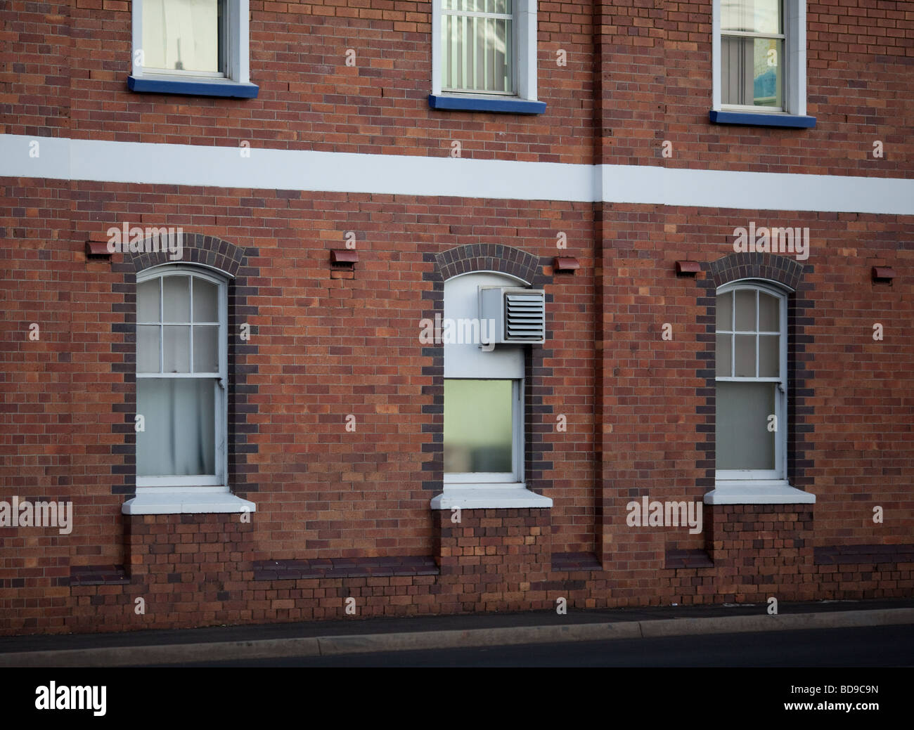 old building wall showing windows and sidewalk Stock Photo