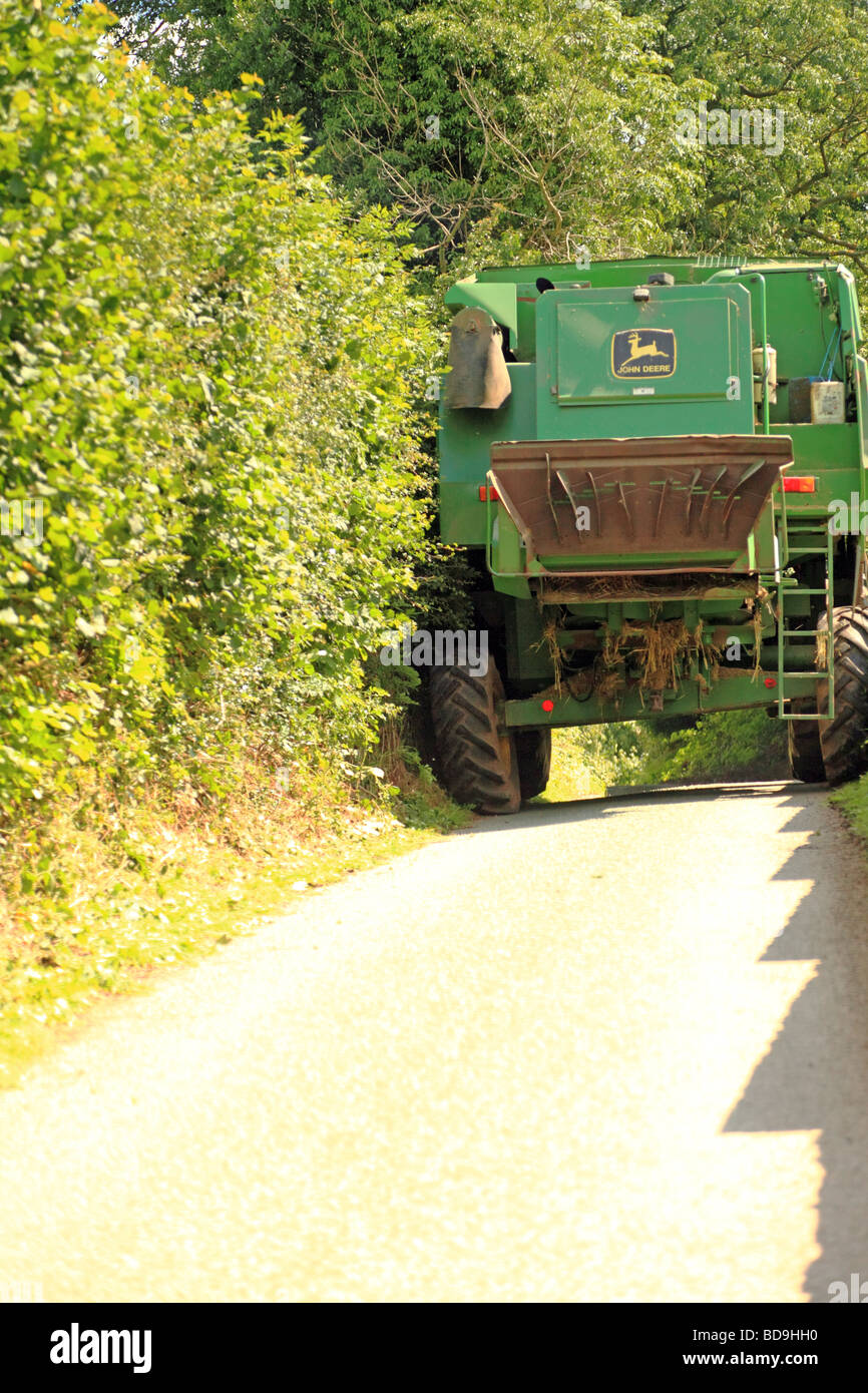 A John Deere combine harvester blocks a narrow country lane Stock Photo